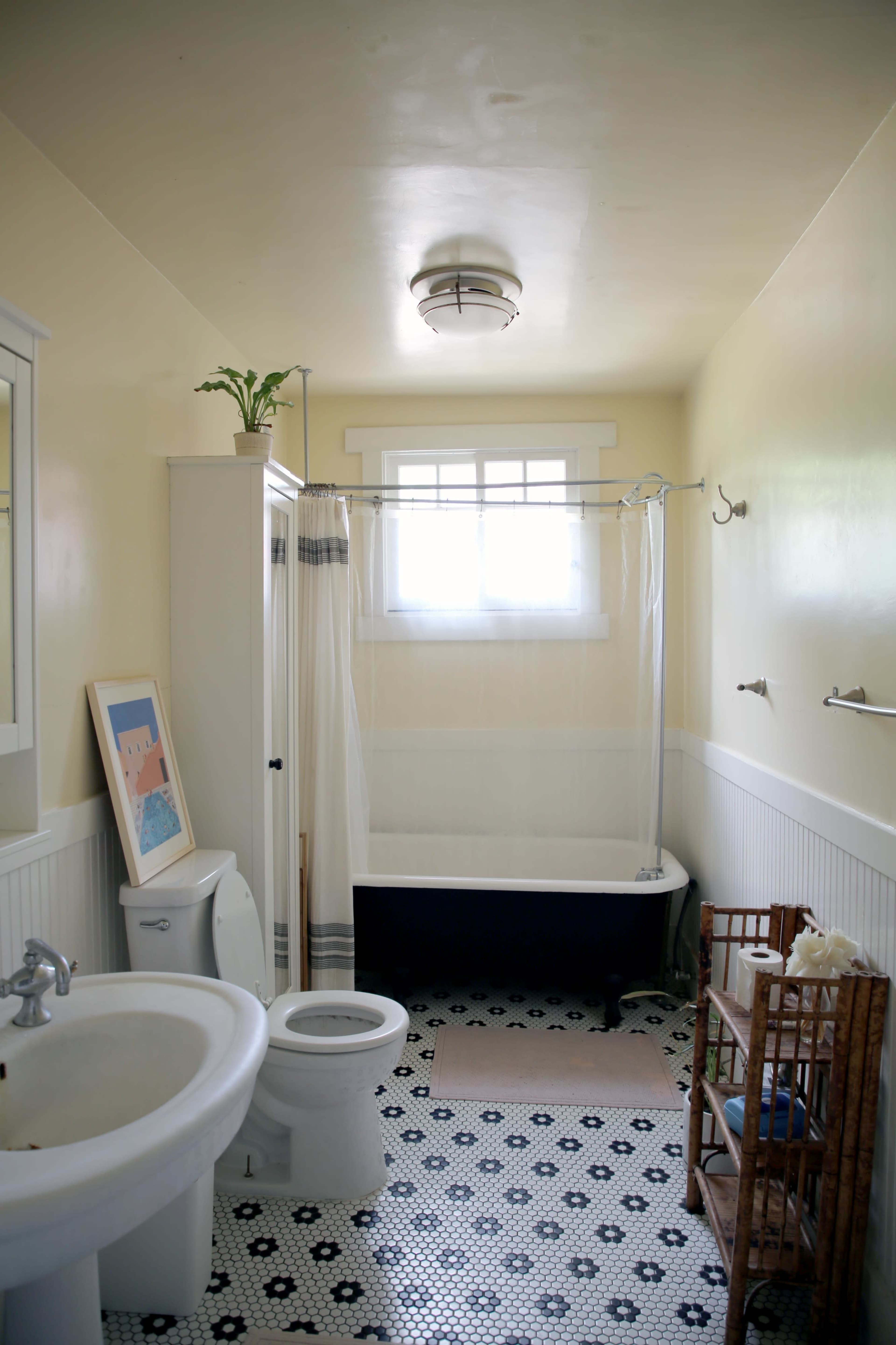 A bathroom featuring a bathtub with a shower curtain, a toilet, a sink, and patterned tile flooring.