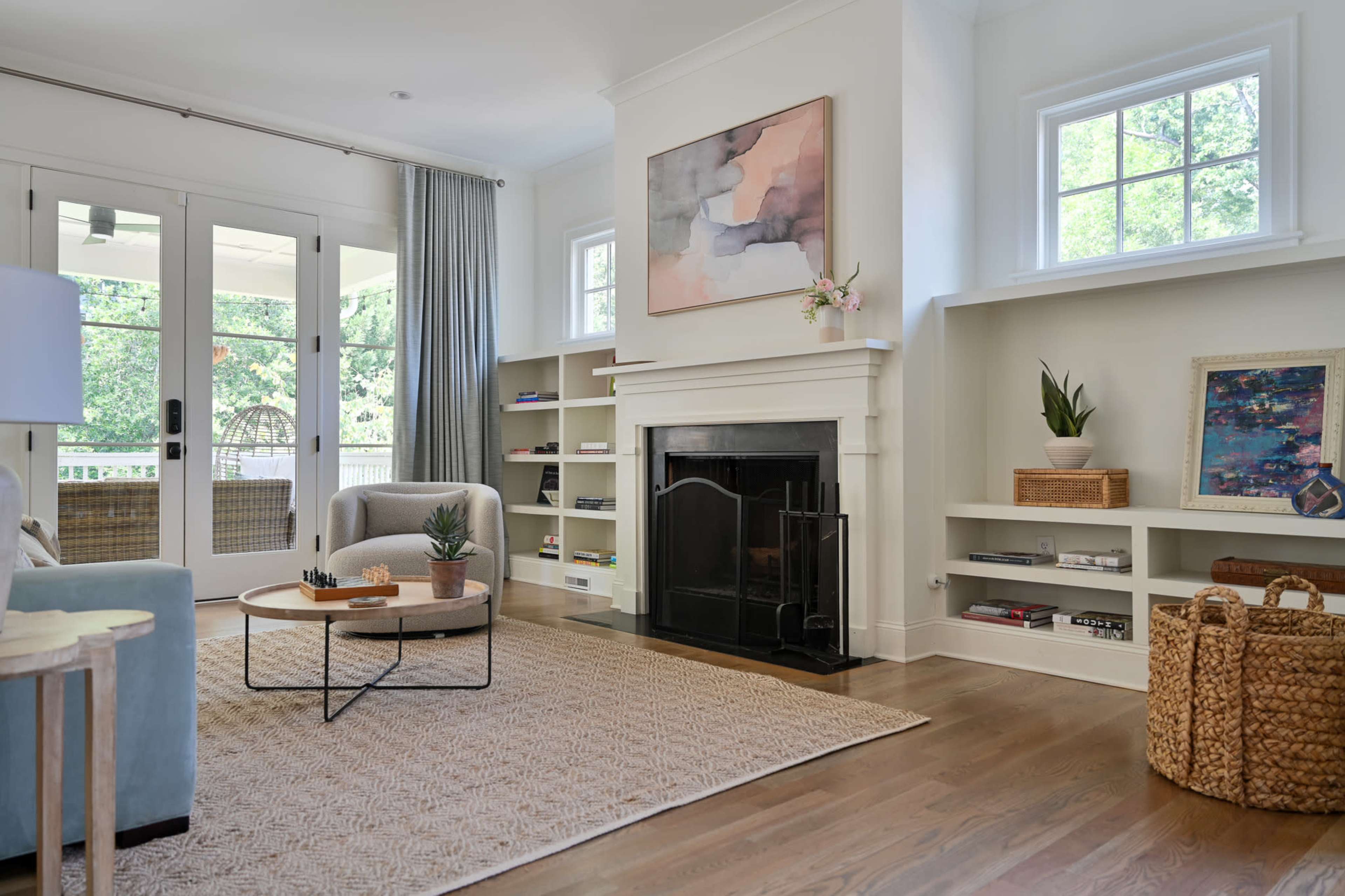A modern living room featuring a light-colored sofa, a round coffee table, a fireplace, and built-in shelves with decorative items.