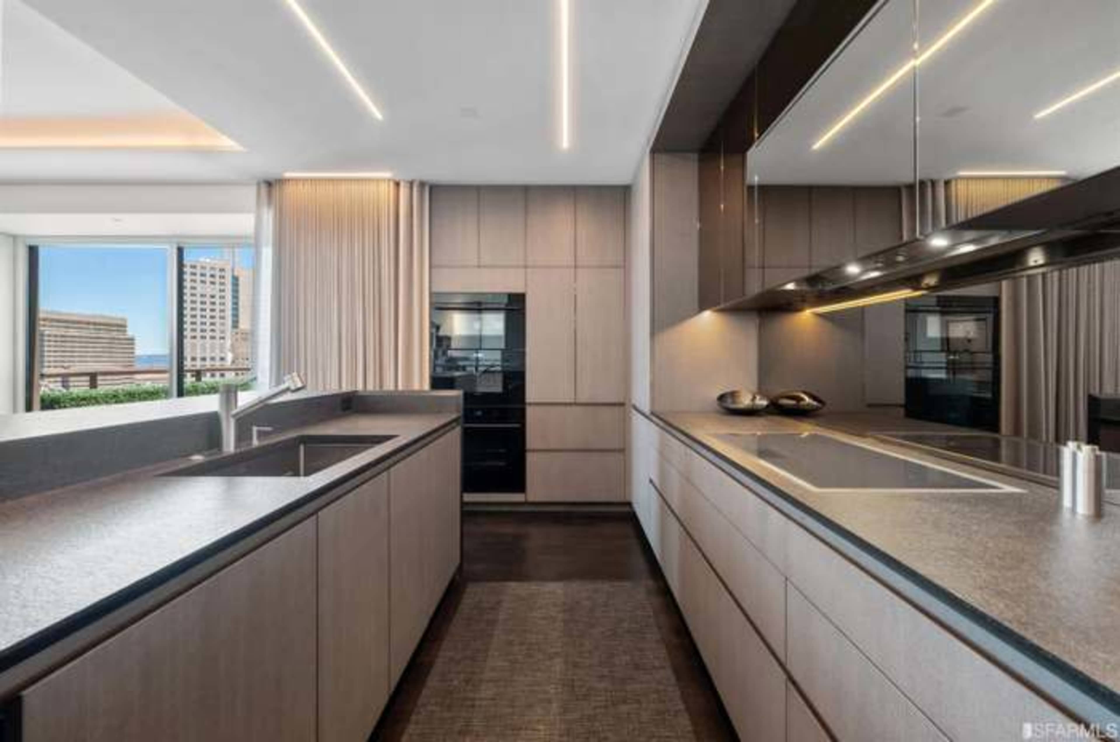 The modern kitchen features sleek cabinetry, dual sink areas, and large windows offering city views.