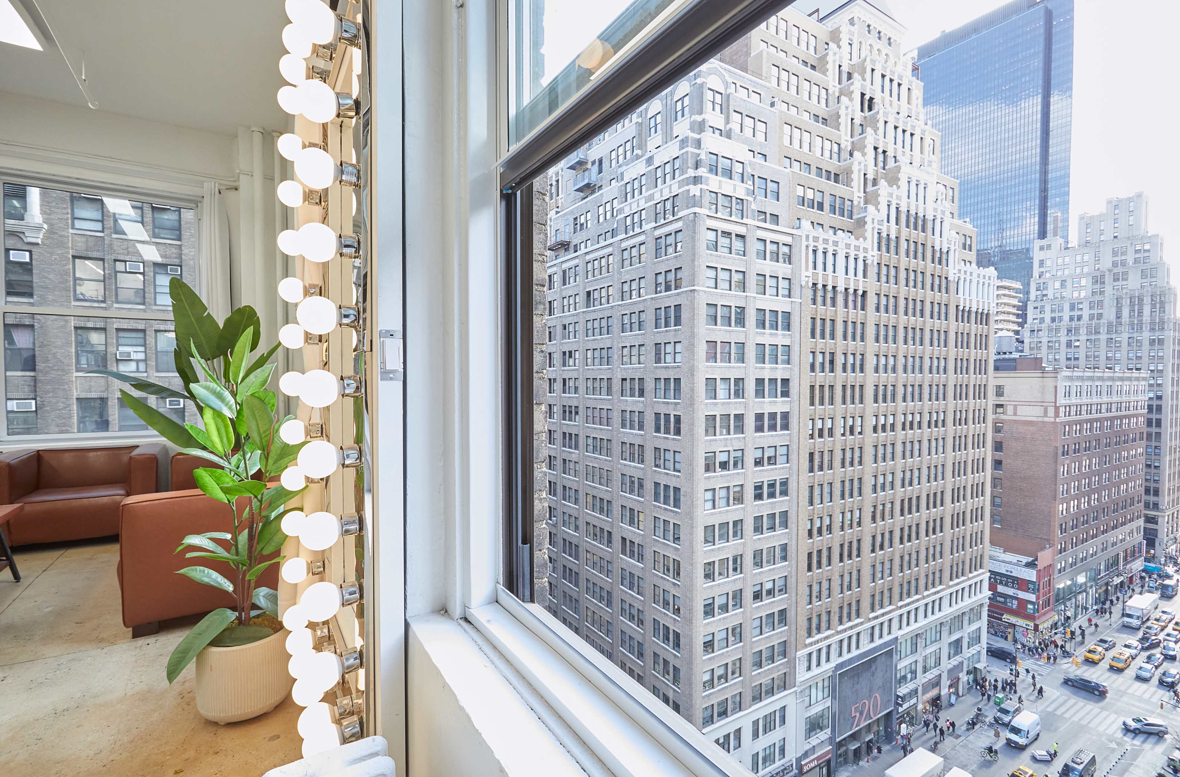 The image shows a view from a window, featuring a cityscape with tall buildings and a street below.