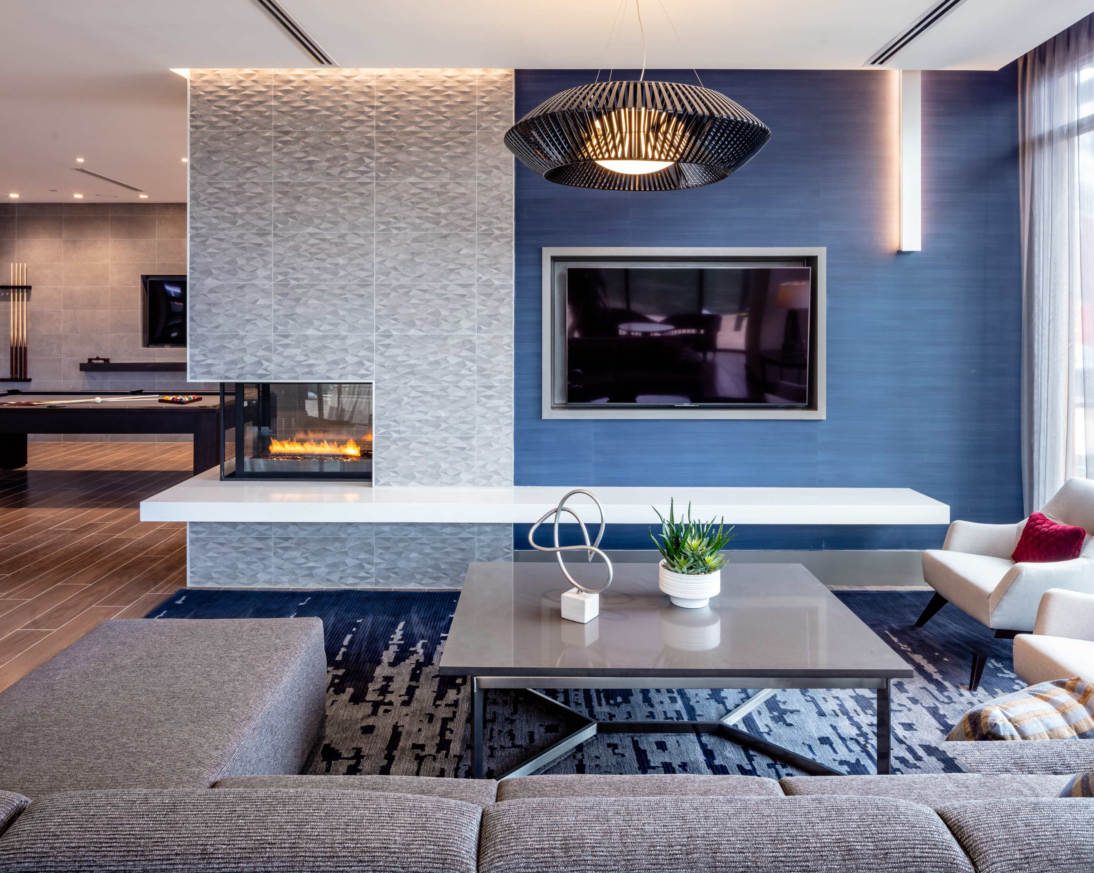 A modern living room featuring a large wall-mounted television, a minimalist coffee table, and a decorative fireplace.