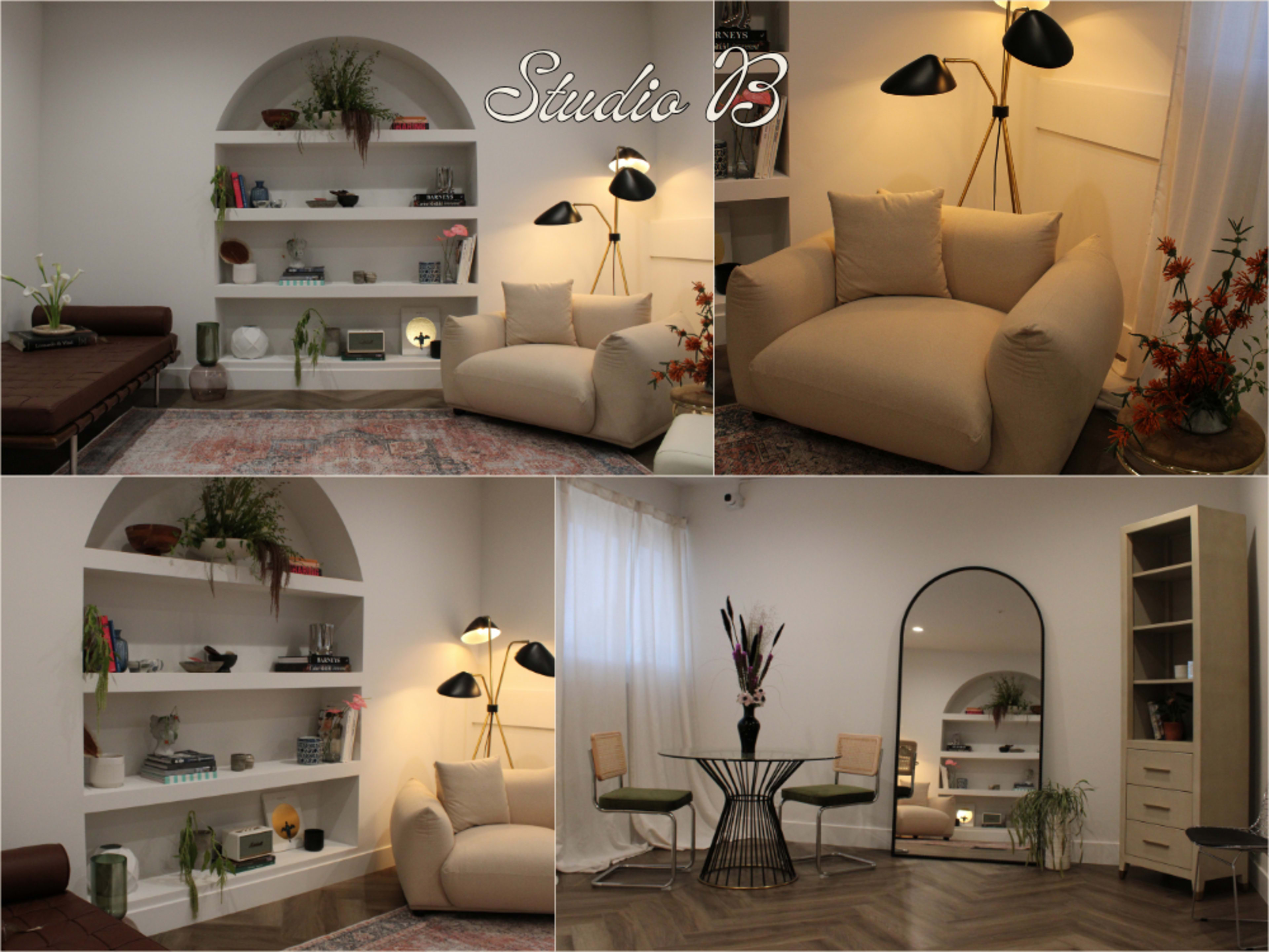 The image displays a modern, well-lit interior design featuring a cozy seating area with plush furniture, decorative shelves, and a dining table surrounded by chairs.