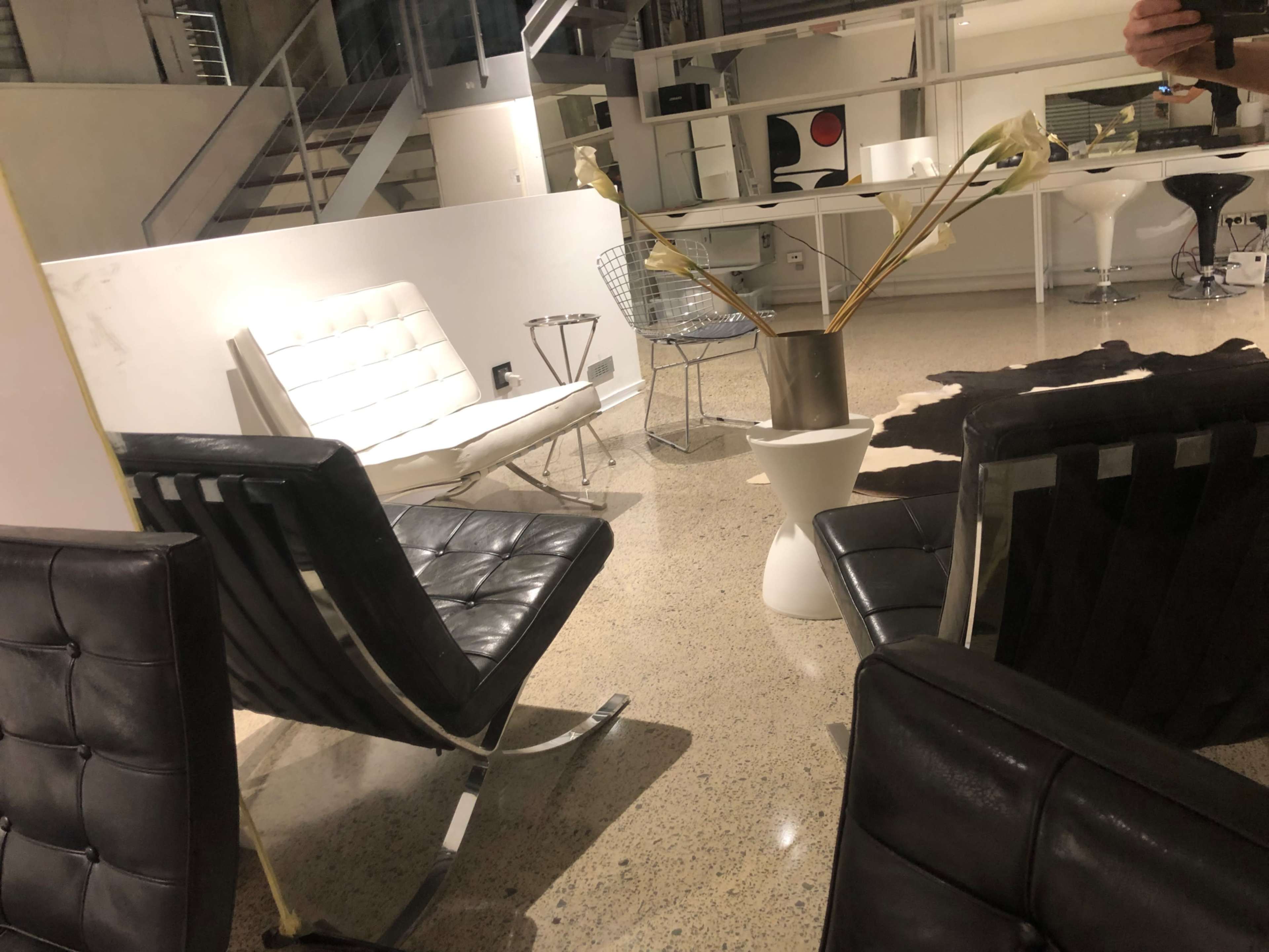 The image shows a modern interior space with various seating options, including a white sofa and black chairs, set on a polished floor.