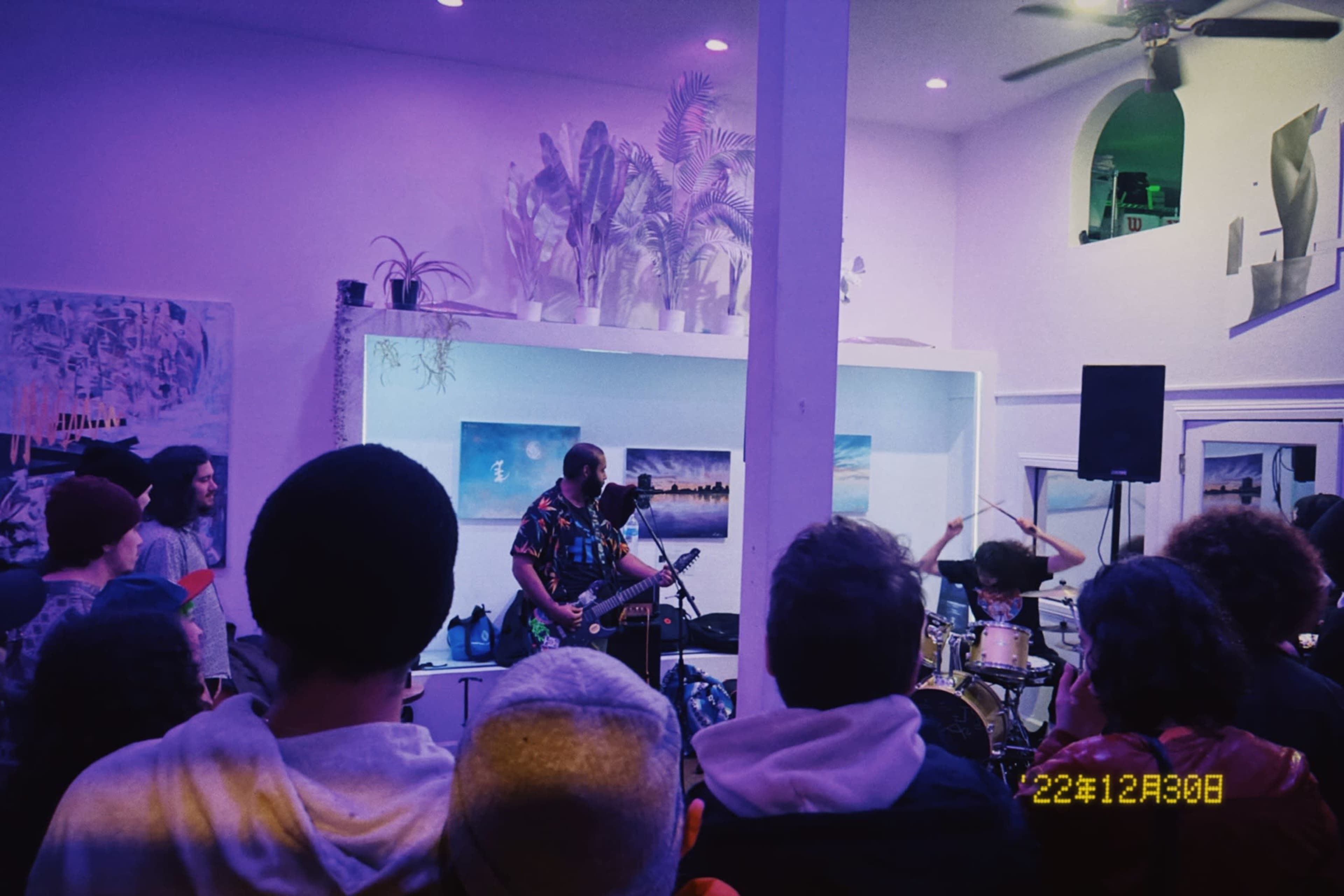 A band performs in a small, brightly lit venue filled with an audience.