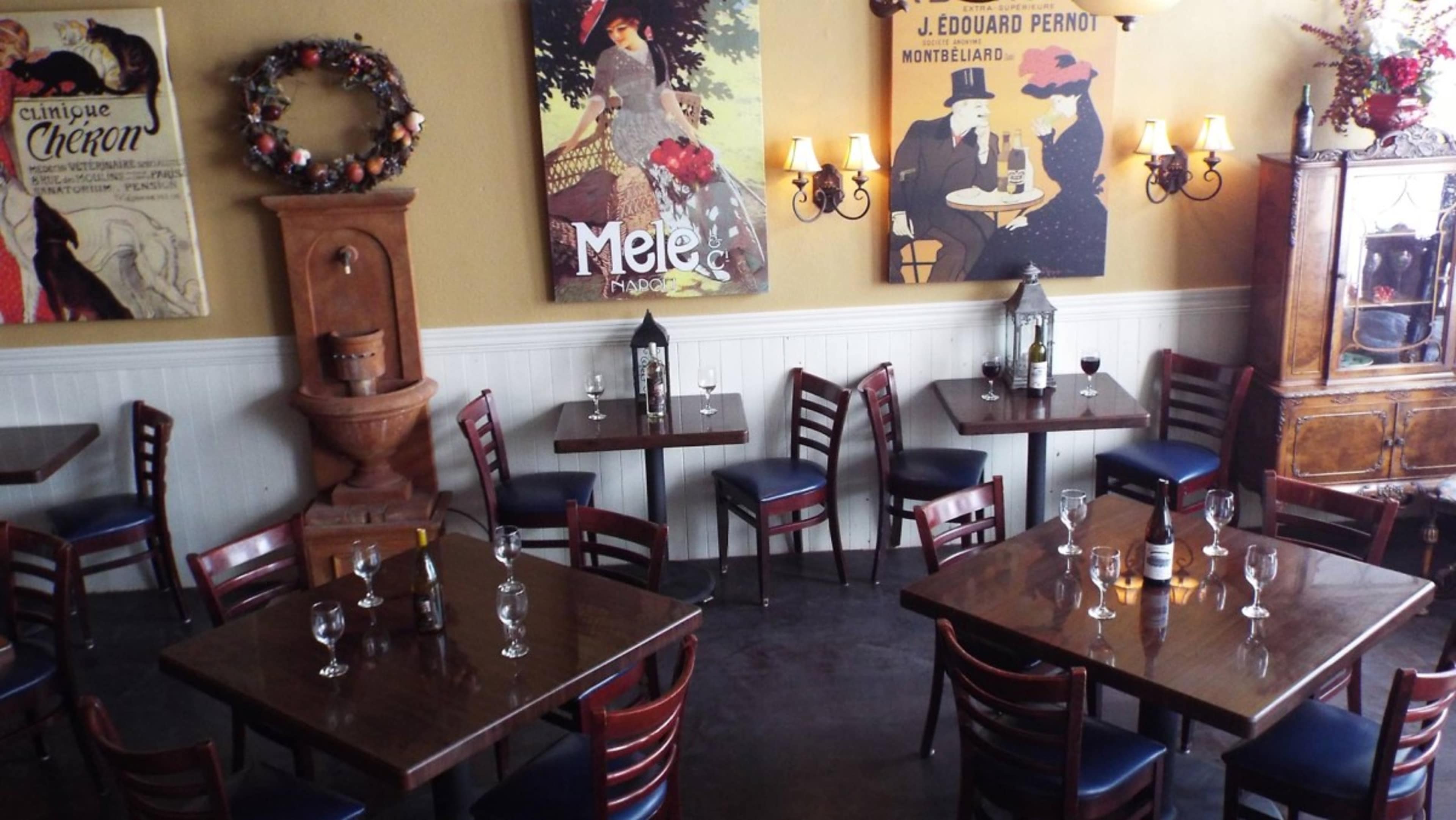 A cozy restaurant interior featuring wooden tables and chairs, decorative wall art, and a fountain in the corner.