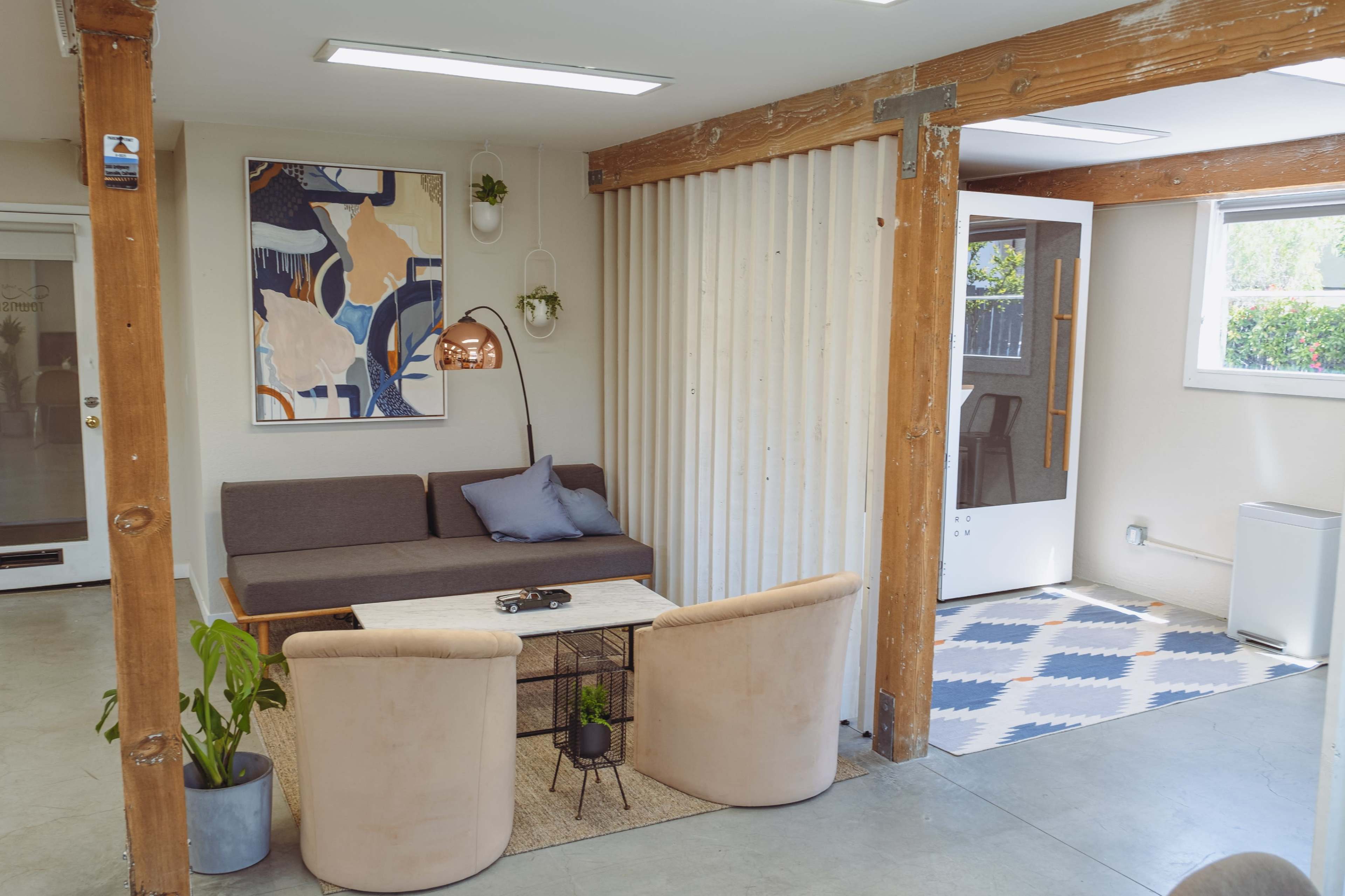 A modern living space with a sofa, a coffee table, a floor lamp, and a small seating area on a patterned rug.