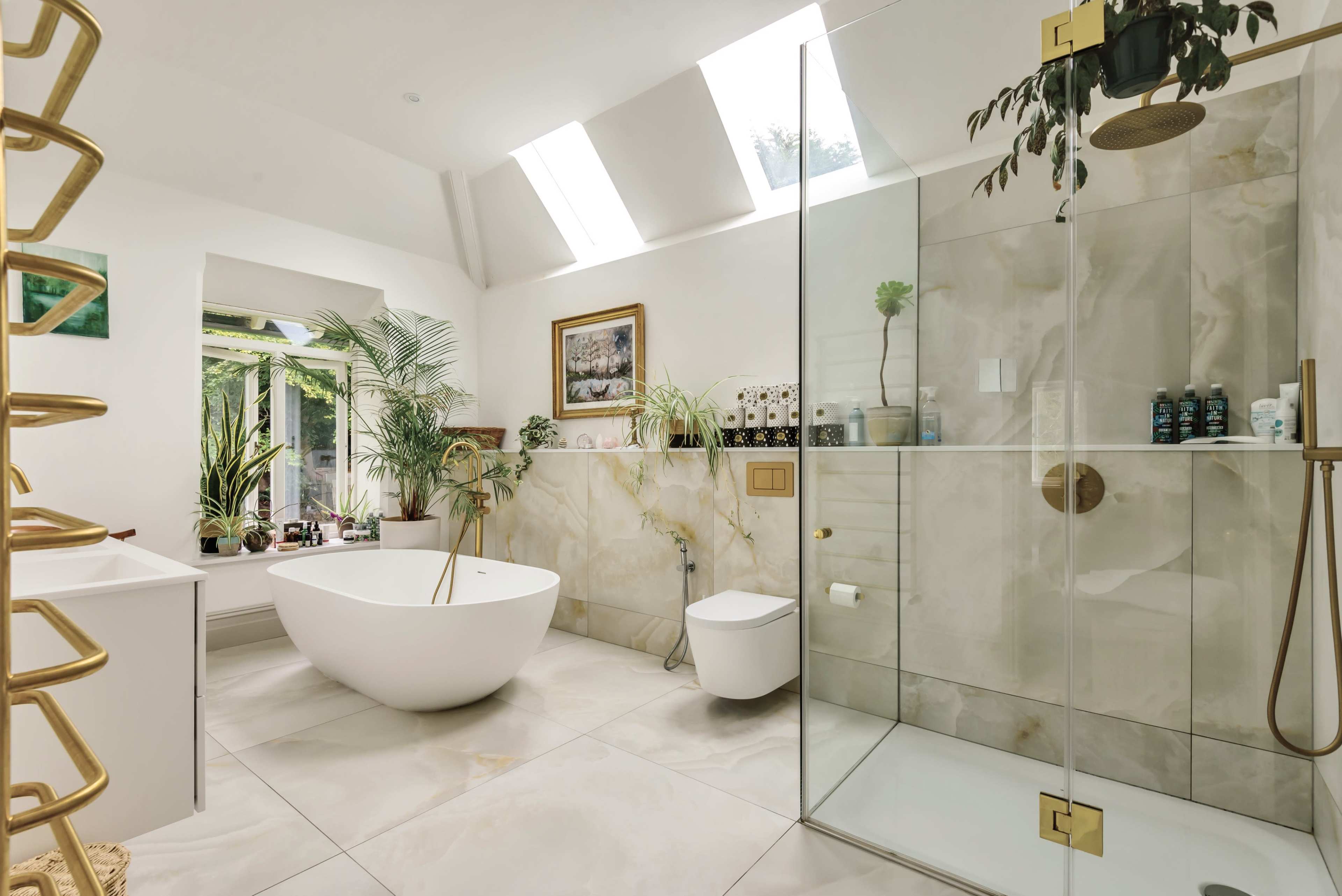 A modern bathroom with a freestanding white bathtub, a glass shower enclosure, and large windows that allow natural light to fill the space.