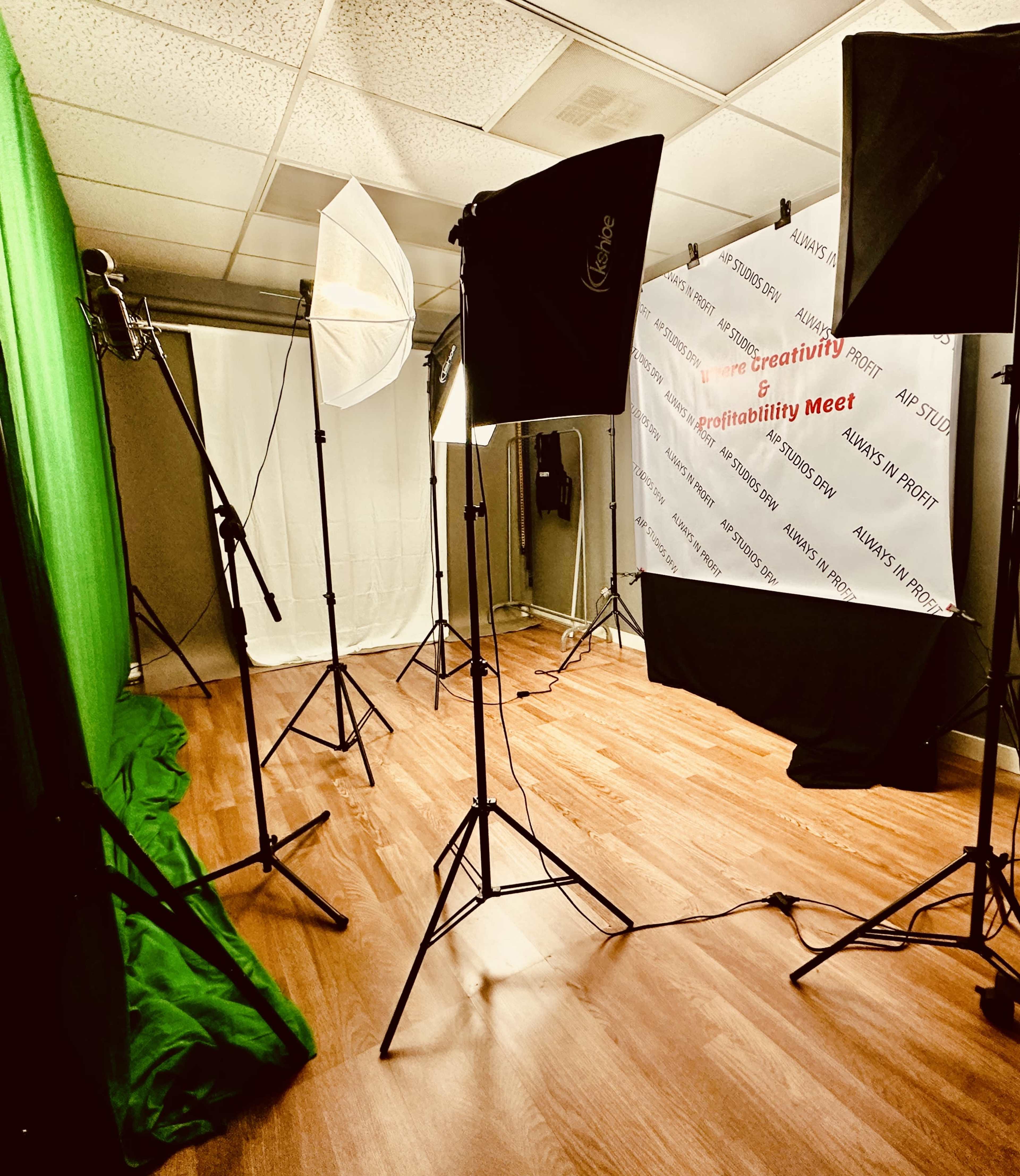 A photography studio with various lighting equipment, a green screen, and a backdrop displaying text.