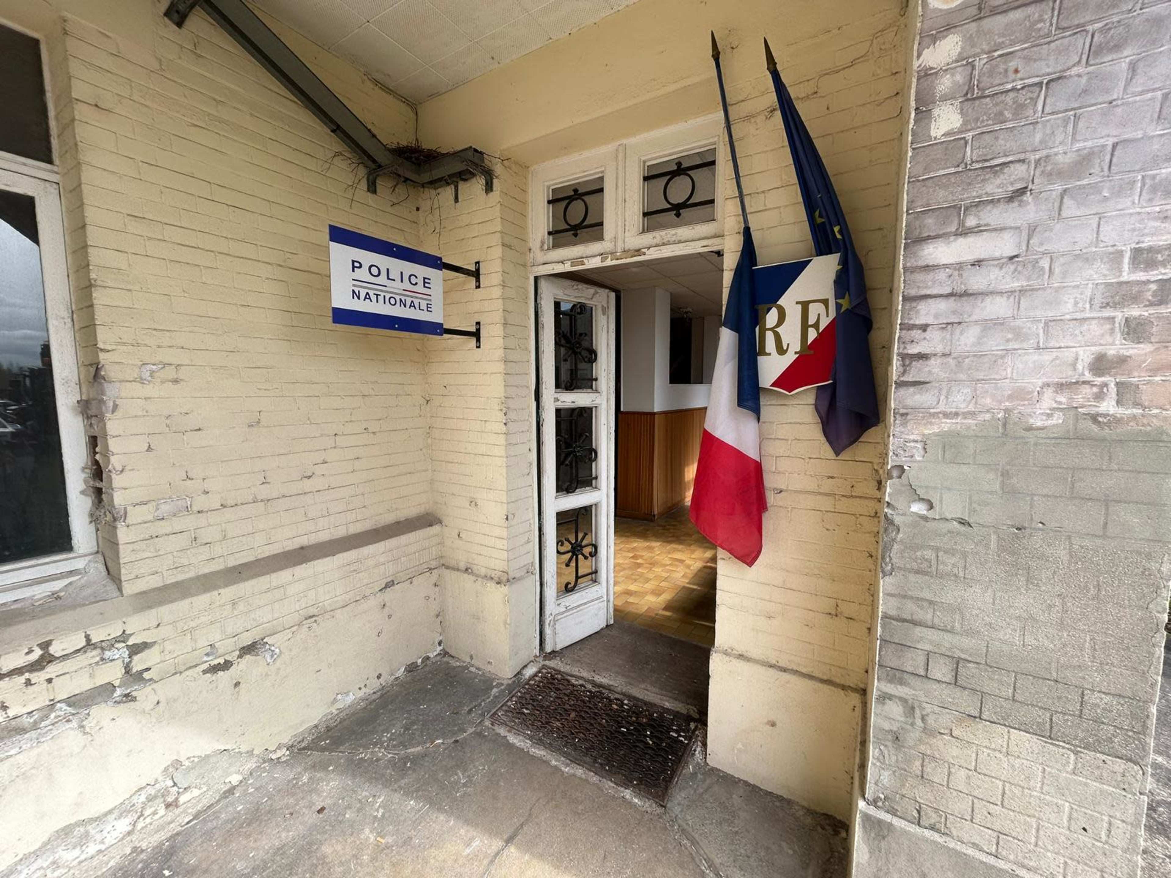 The entrance of a police station features the French national flag, the European Union flag, and a sign reading "Police Nationale."