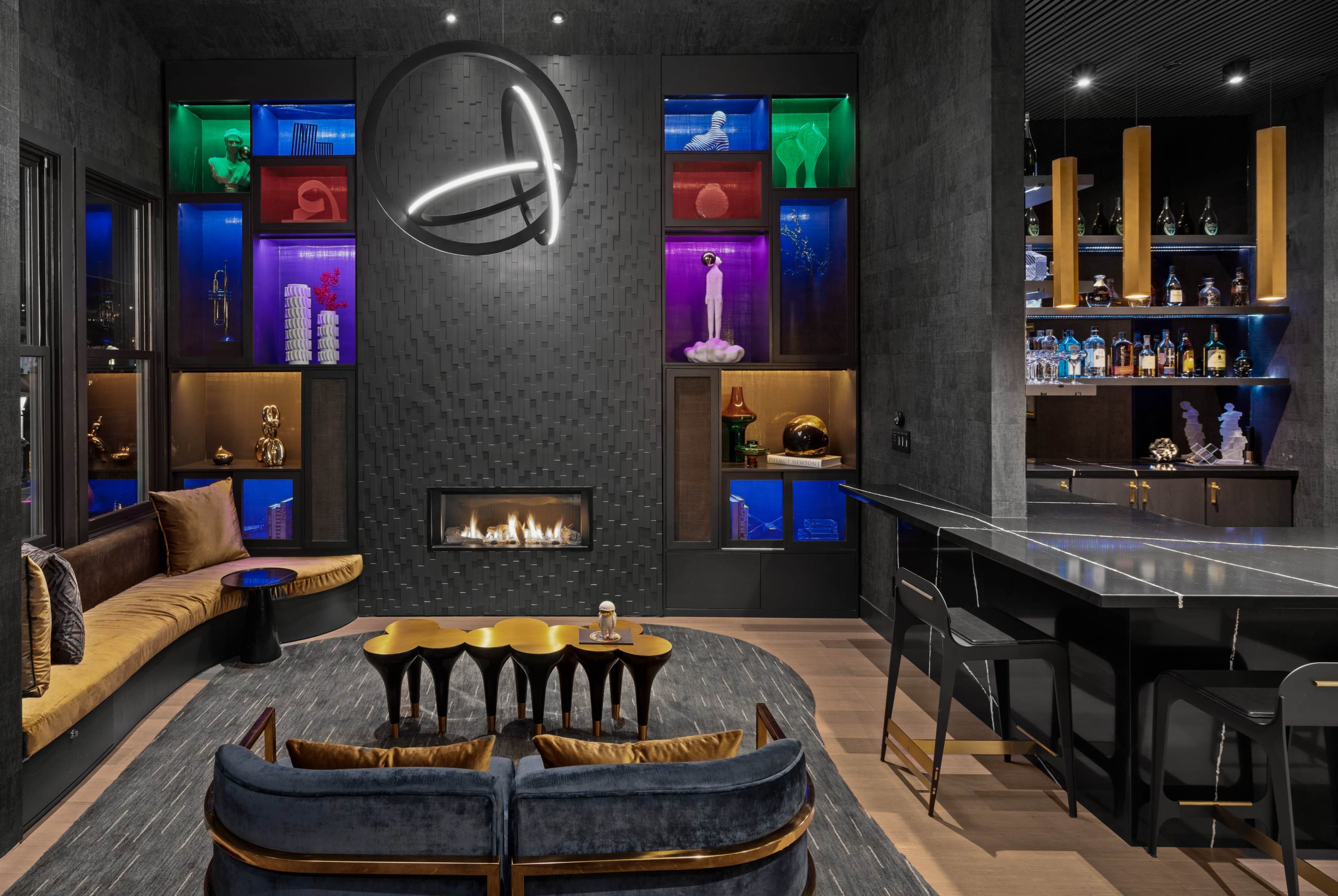 A modern lounge area featuring a sleek fireplace, colorful illuminated shelves, and contemporary furniture arrangements.