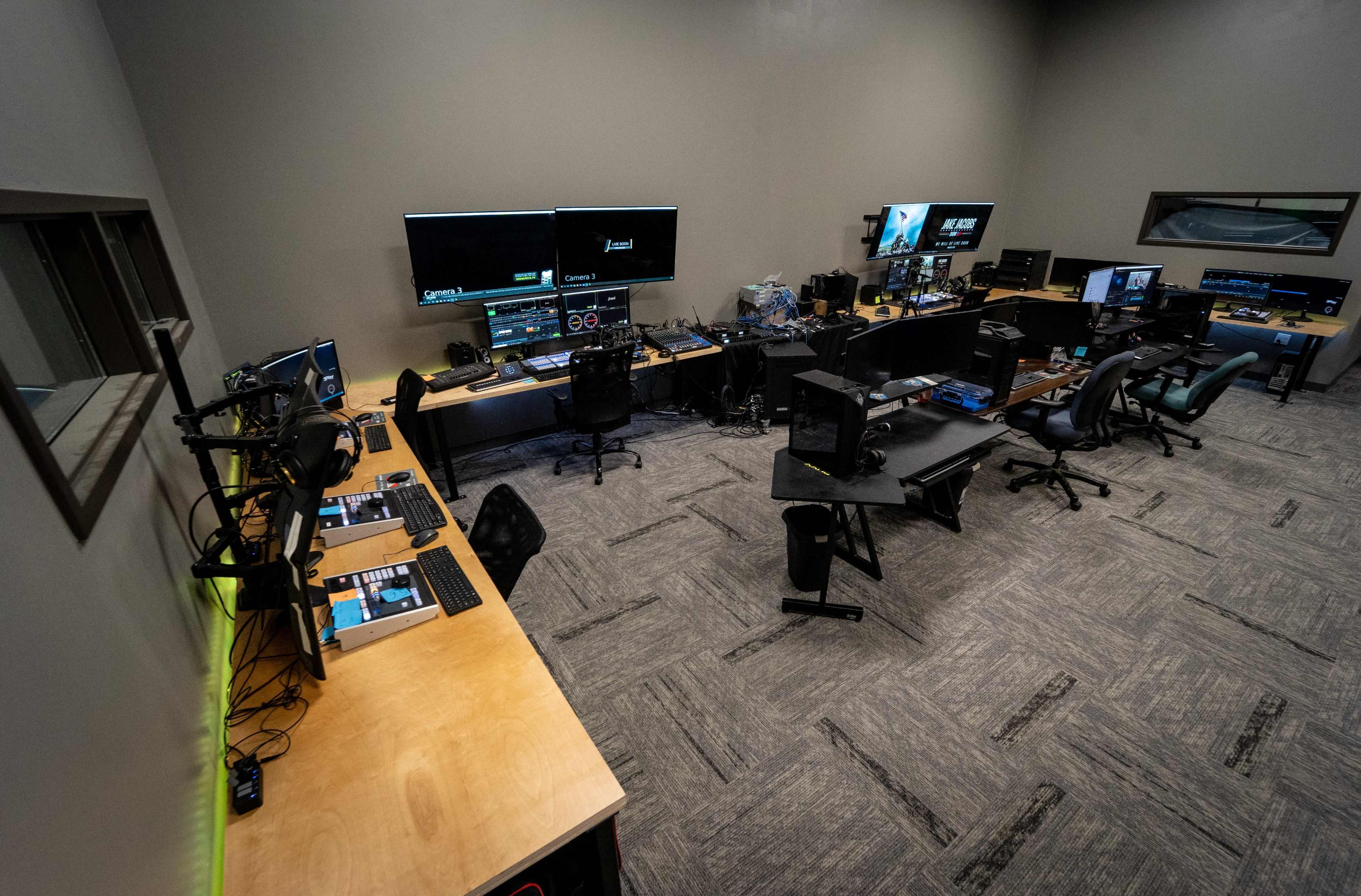 The image shows a spacious editing room equipped with multiple computer stations, large monitors, and professional audio equipment.