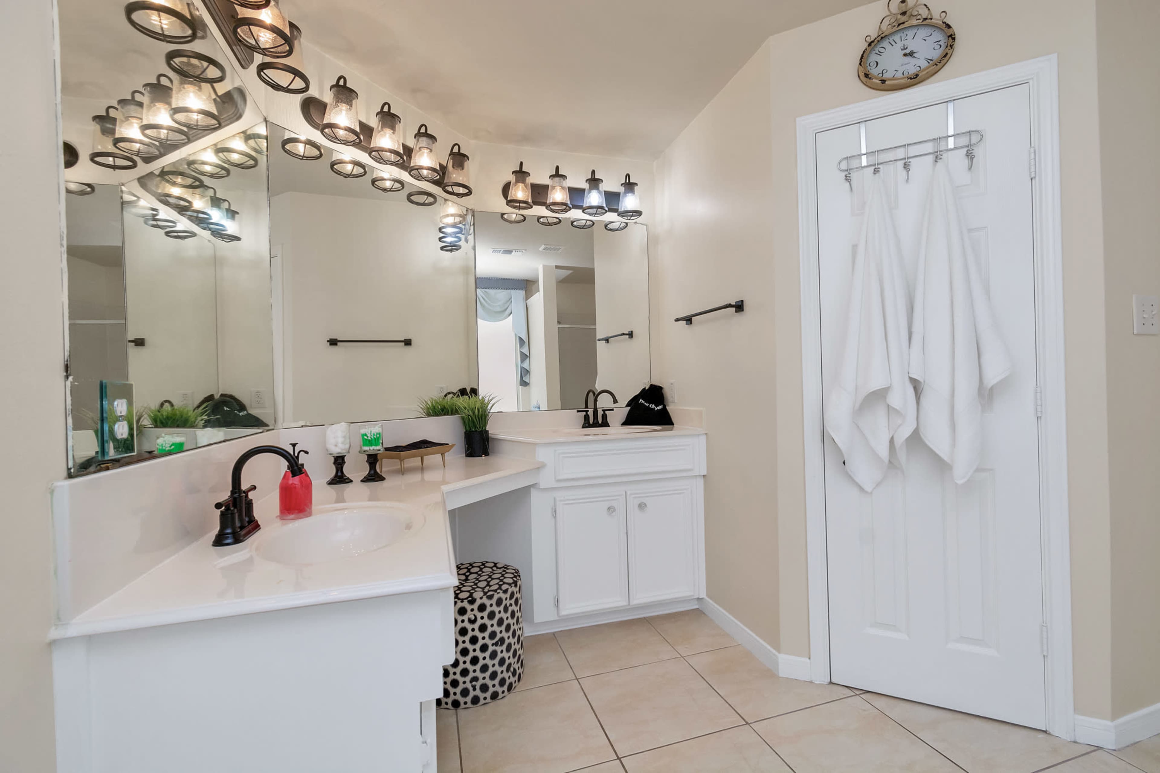 A well-lit bathroom features a spacious countertop, a large mirror, and neatly hung towels.