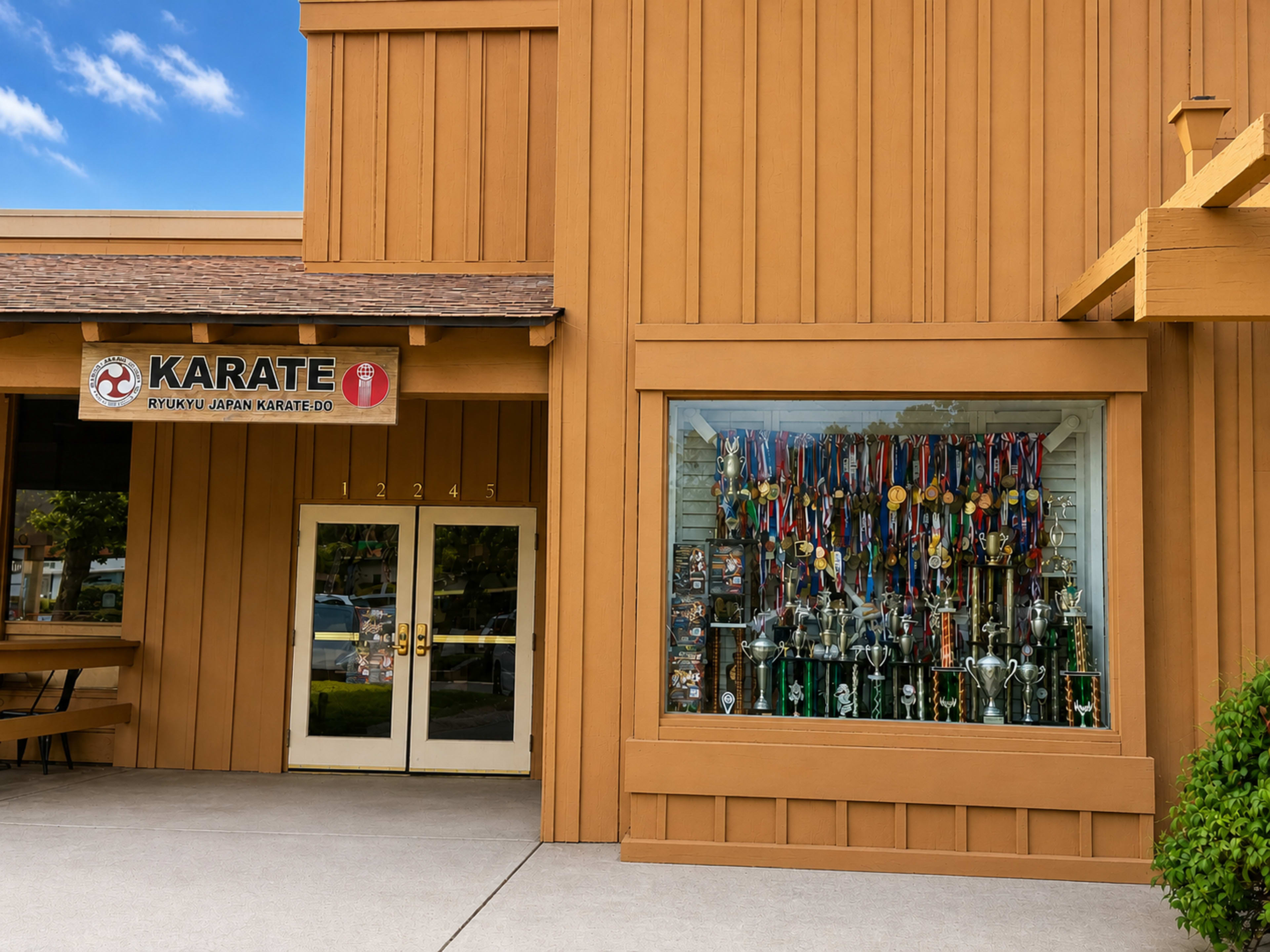 The image shows a karate dojo with a sign reading "Karate" and a display window filled with trophies and medals.