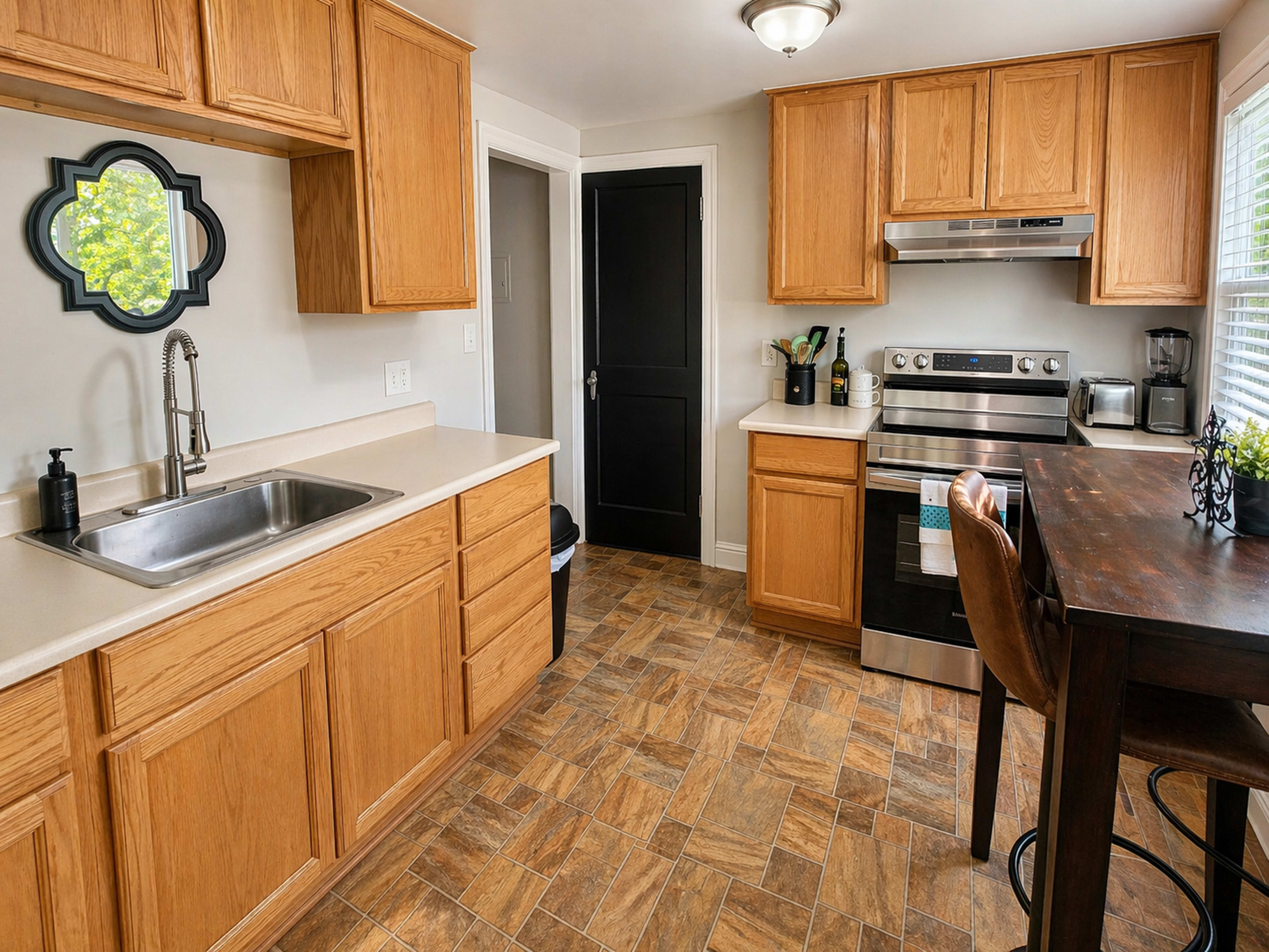 The image shows a modern kitchen featuring wooden cabinets, a stainless steel stove, and a dining table near the window.