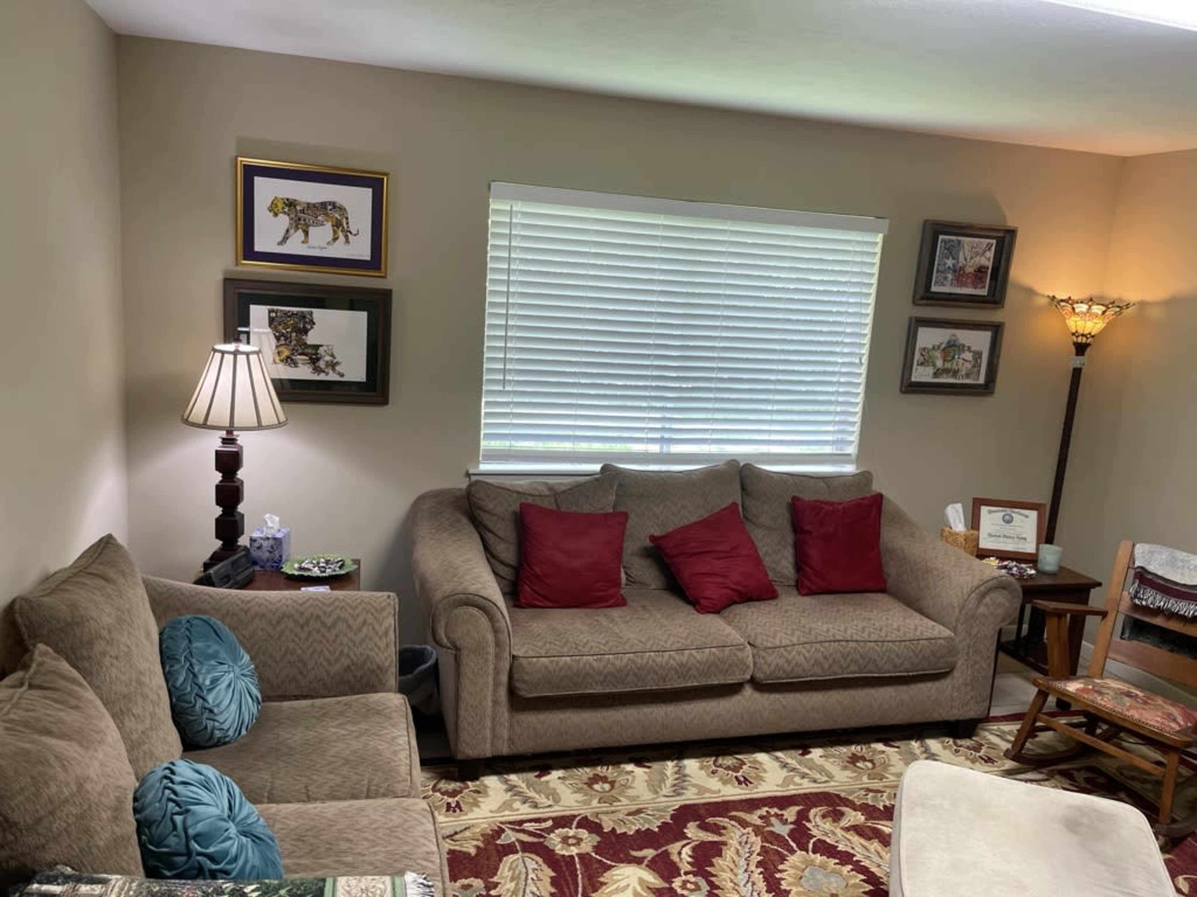The living room features two couches, a decorative rug, framed artwork on the walls, and a lamp beside a side table.