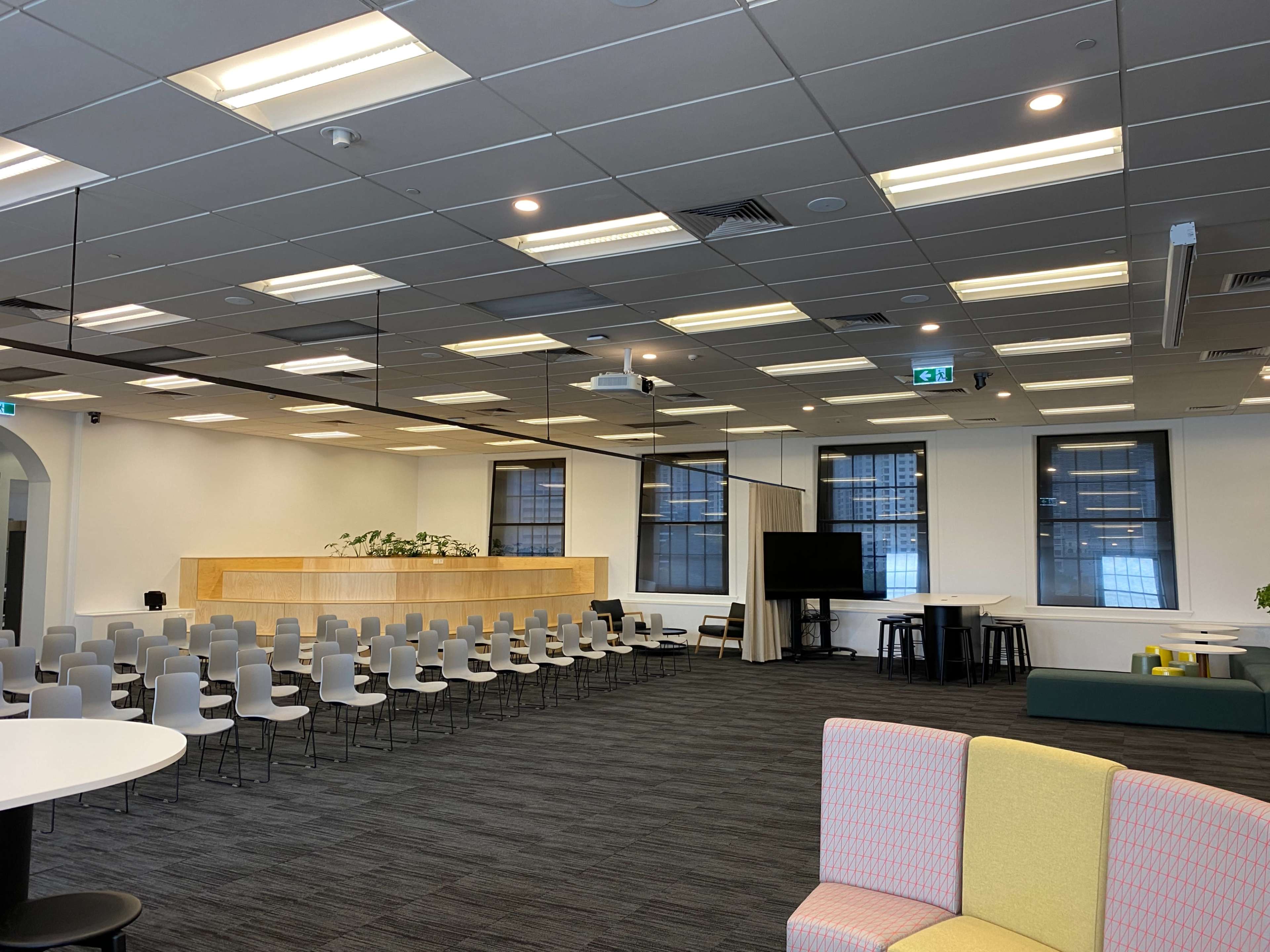 An open office space with rows of chairs arranged for an event, a reception area with a wooden counter, and various seating options including a couch and tables.