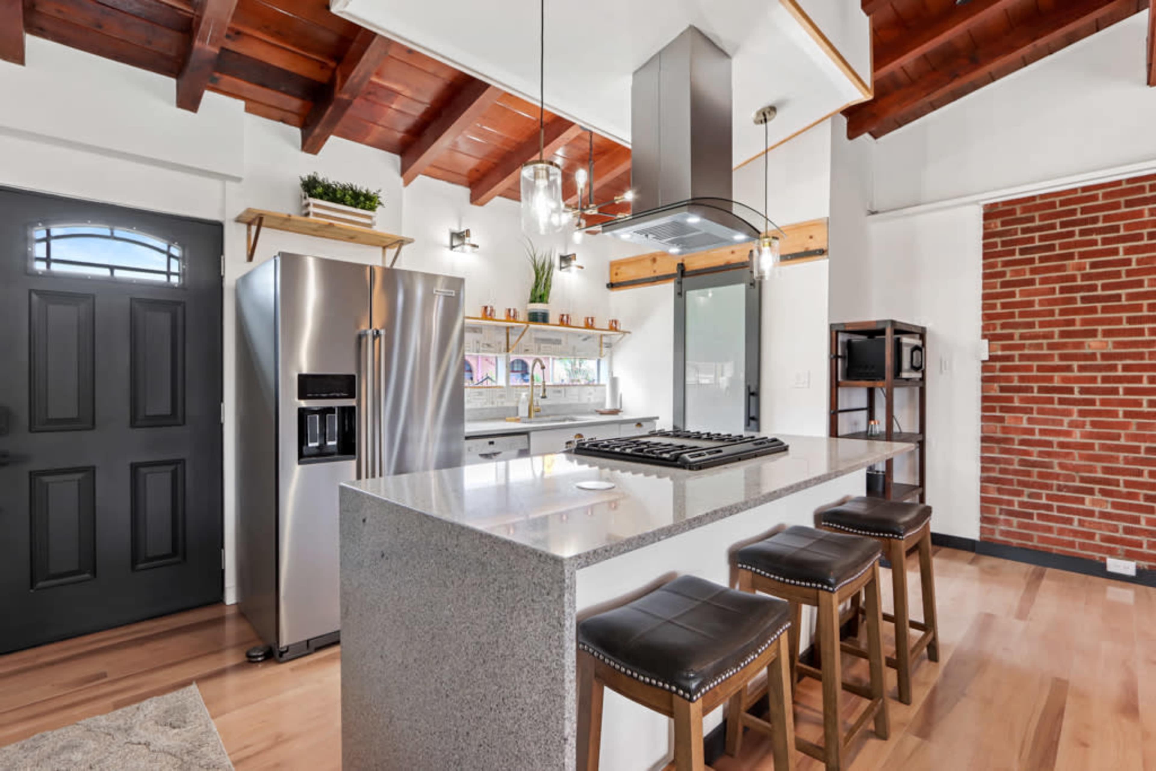 A modern kitchen with a large island, stainless steel appliances, and exposed wooden beams on the ceiling.
