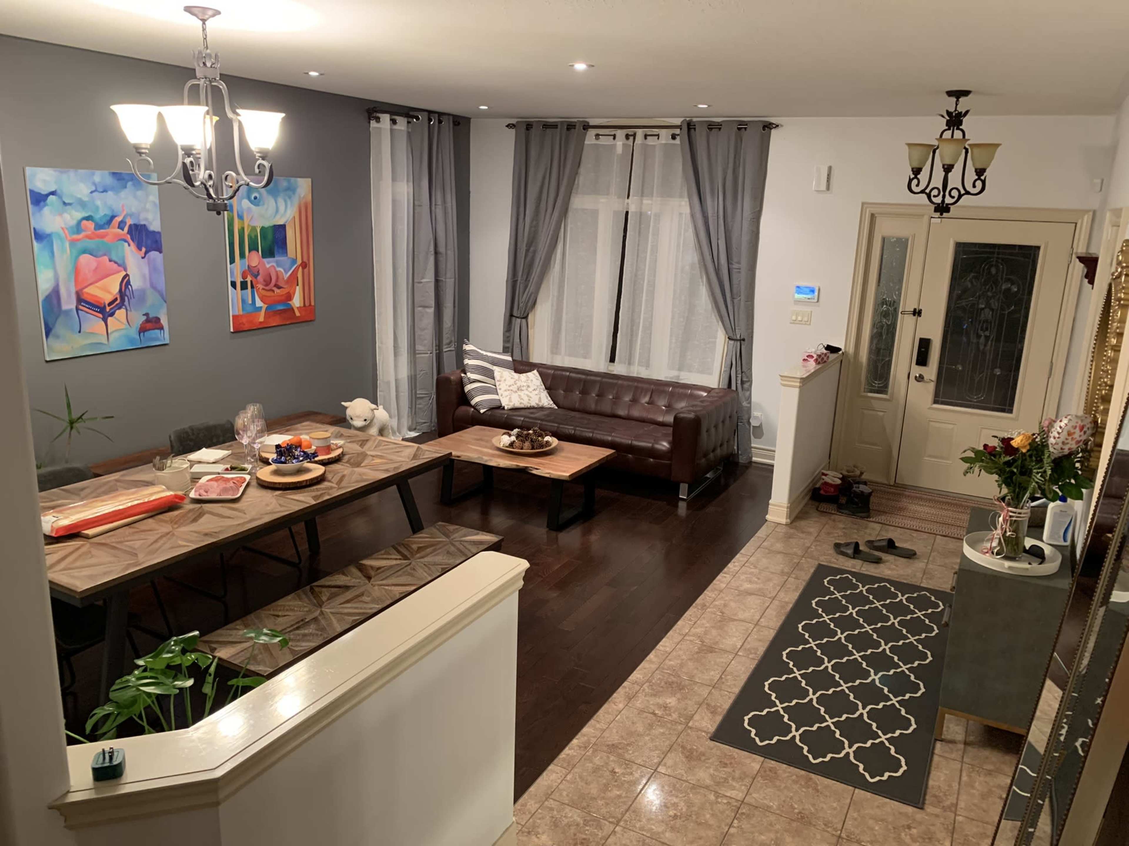 A well-furnished living and dining area with a large table, a dark leather couch, and decorative wall art.