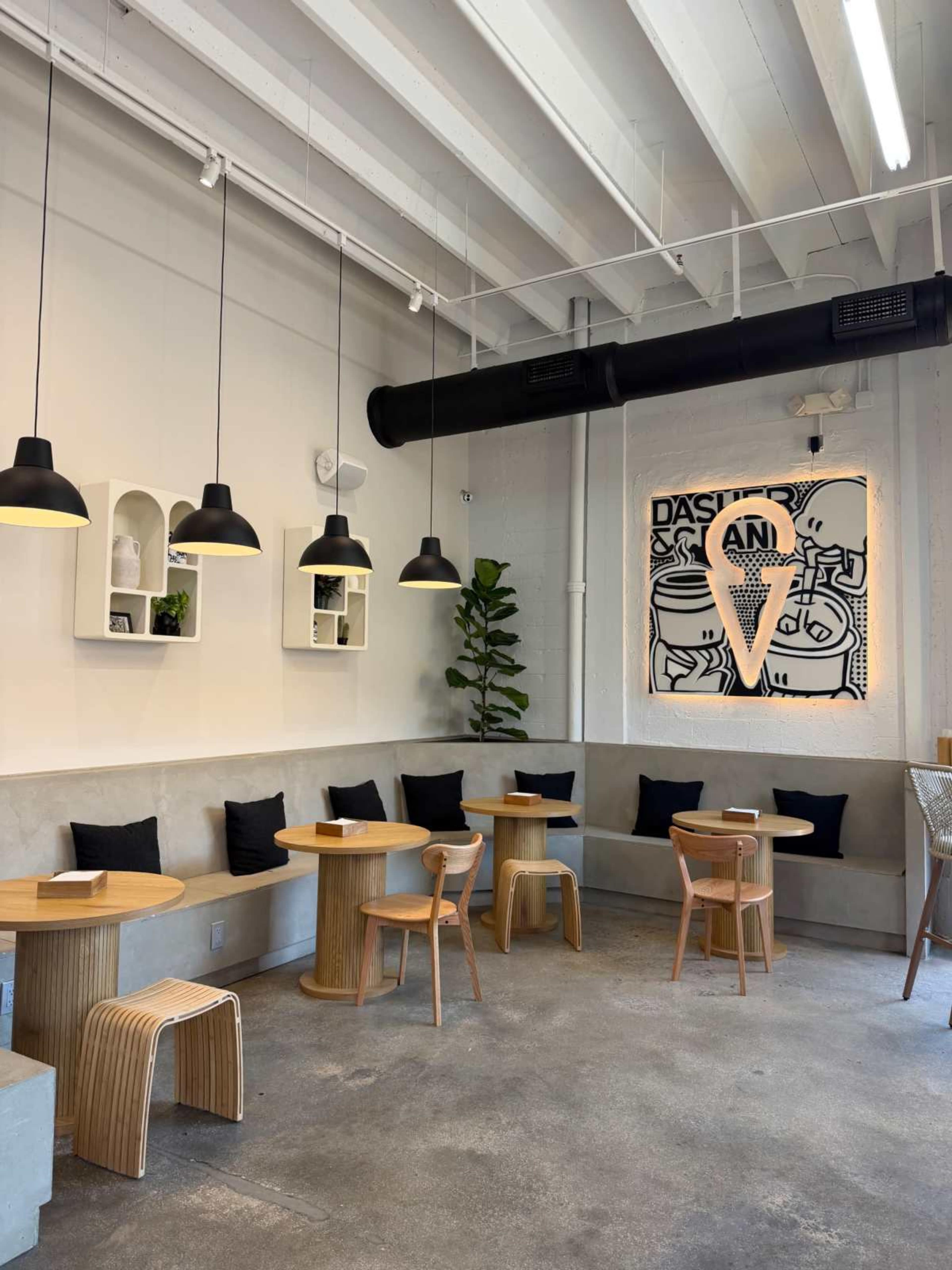 The interior of a modern café features wooden seating arrangements, black accents, and decorative wall art.