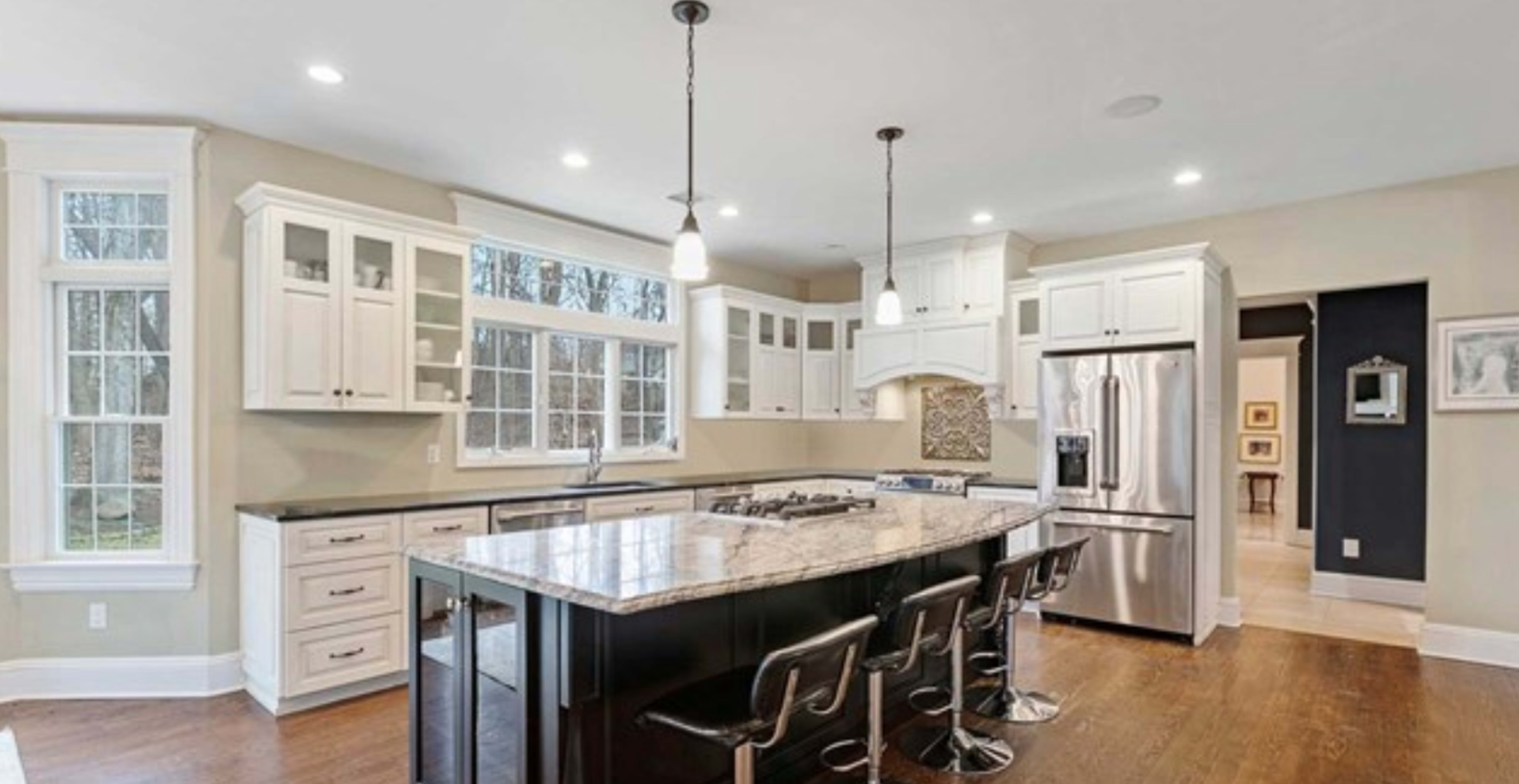 A modern kitchen with white cabinetry, a large island, and stainless steel appliances.