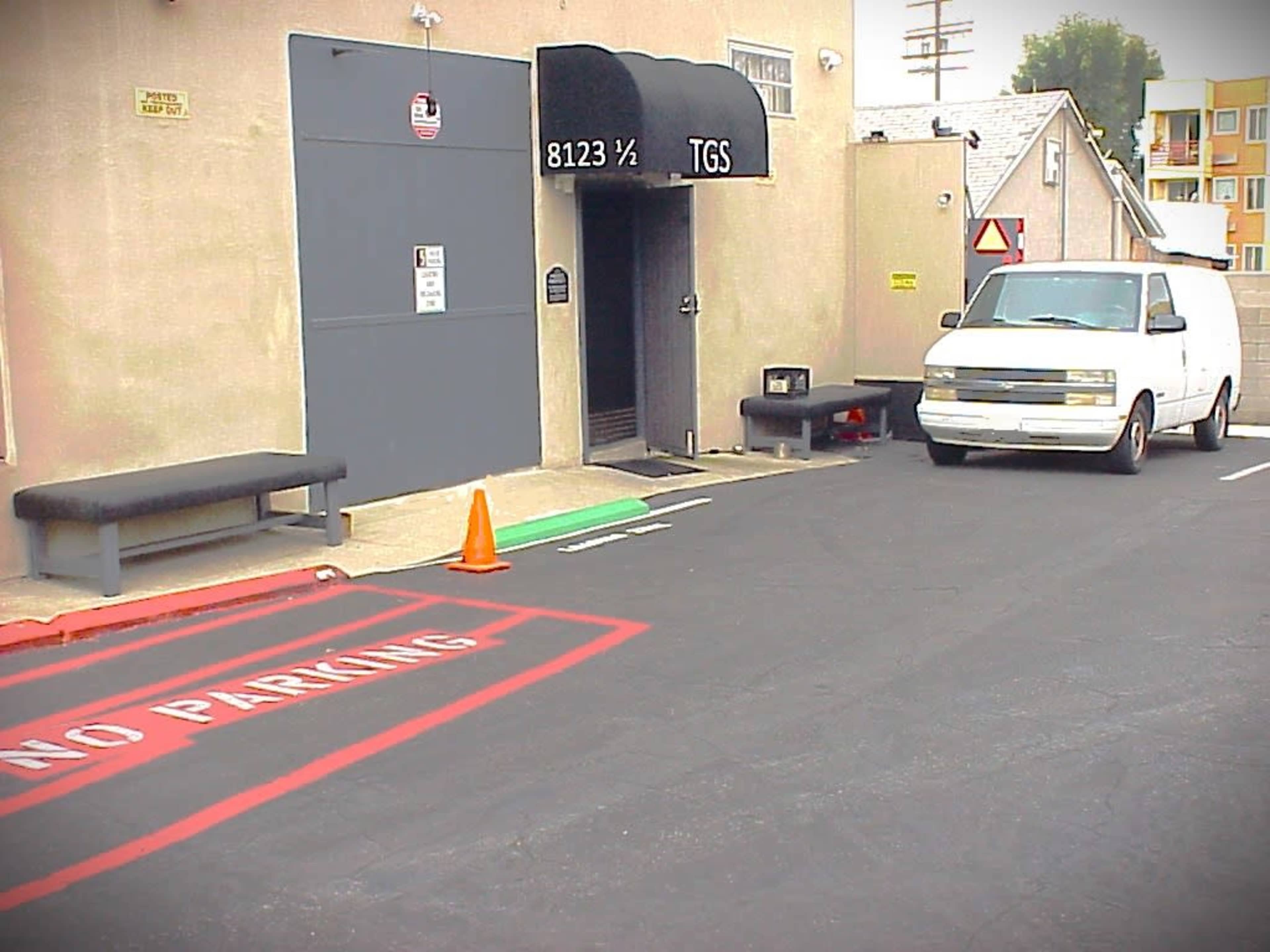 The image shows a parking lot with a white van parked near a "No Parking" zone, alongside an entrance marked "TGS."