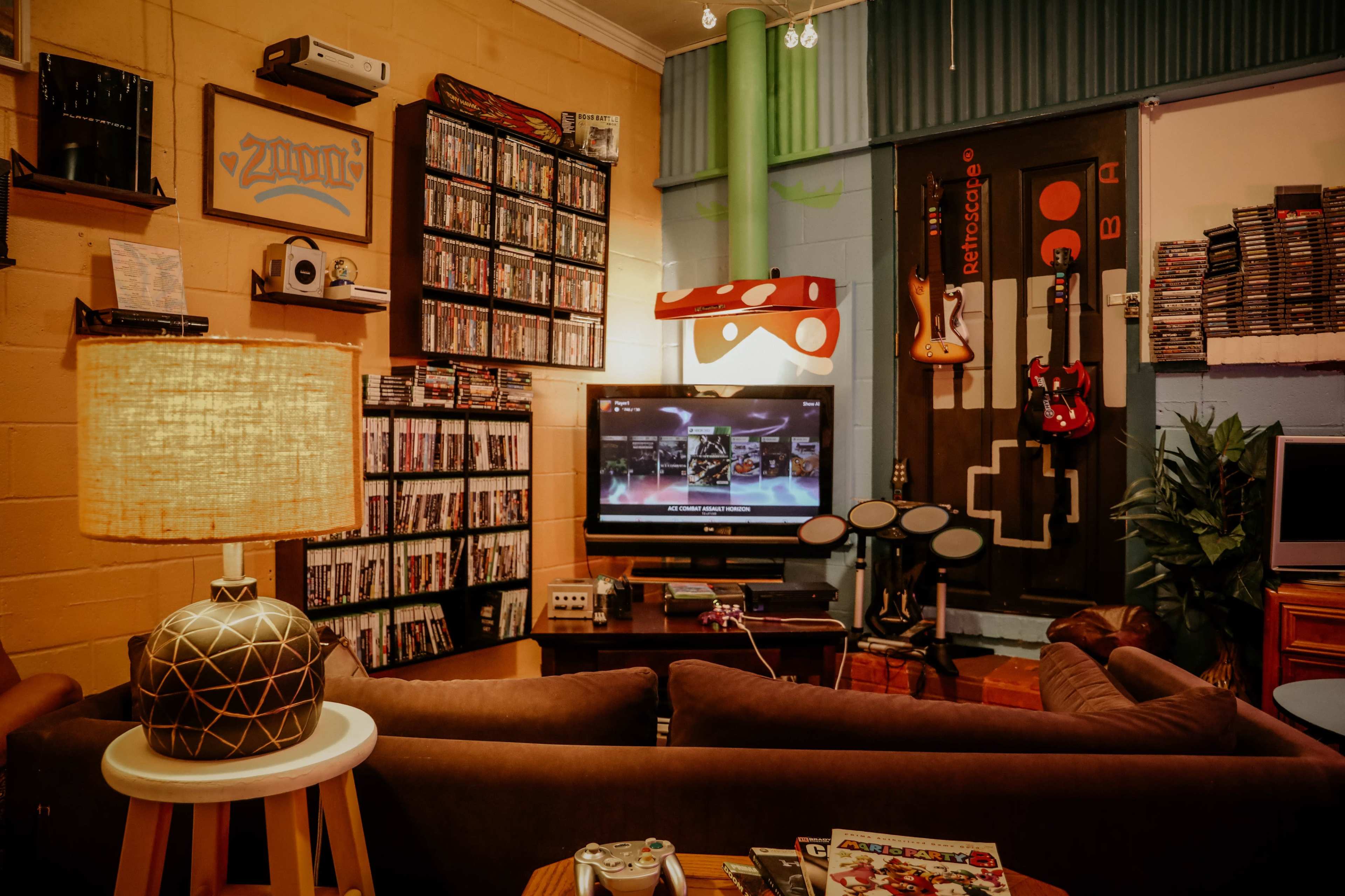 A cozy entertainment room features a large TV, gaming setup, a collection of DVDs, and musical instruments on display.