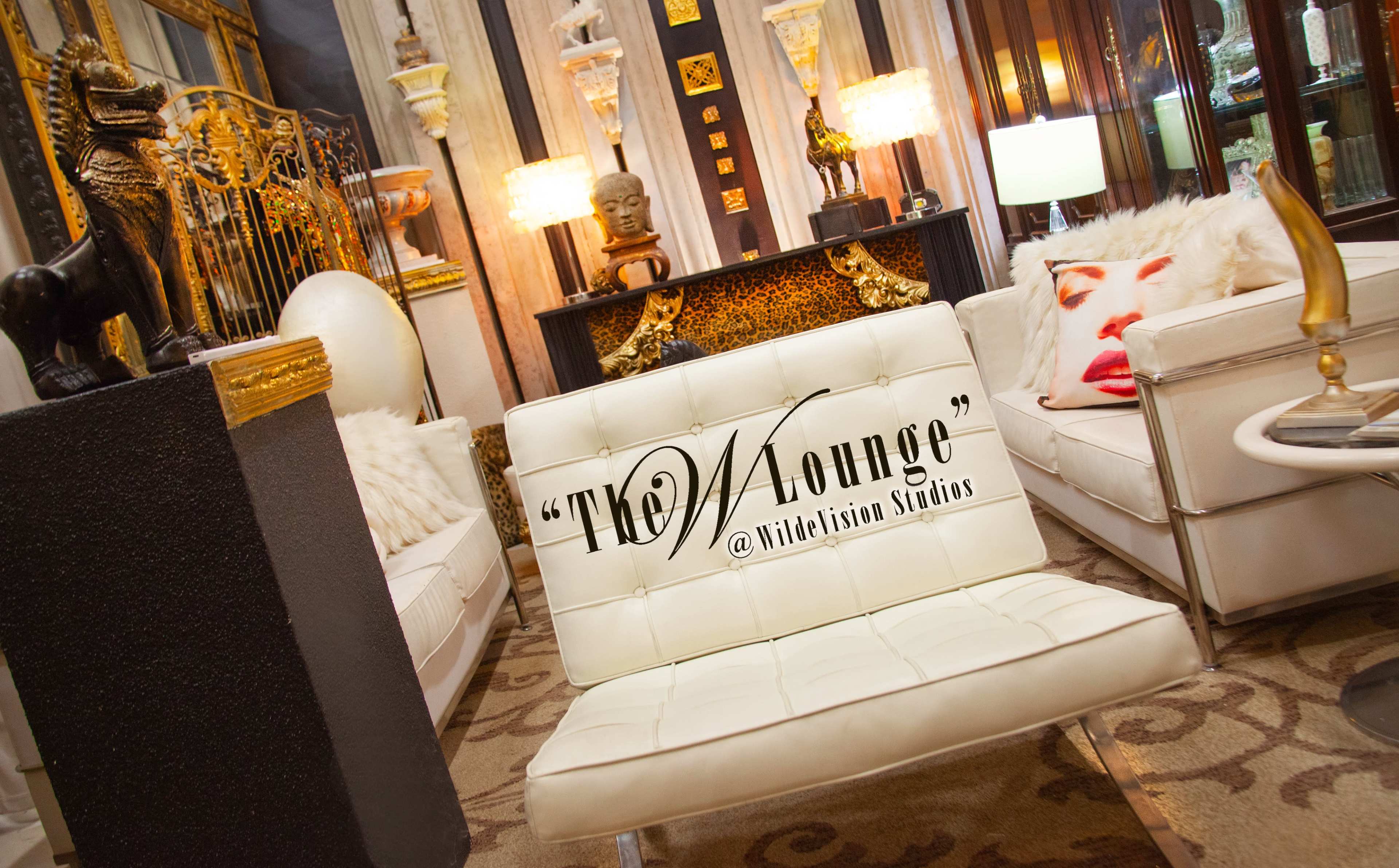 The image shows a modern lounge area featuring white furniture, decorative art pieces, and a stylish setting with ambient lighting.