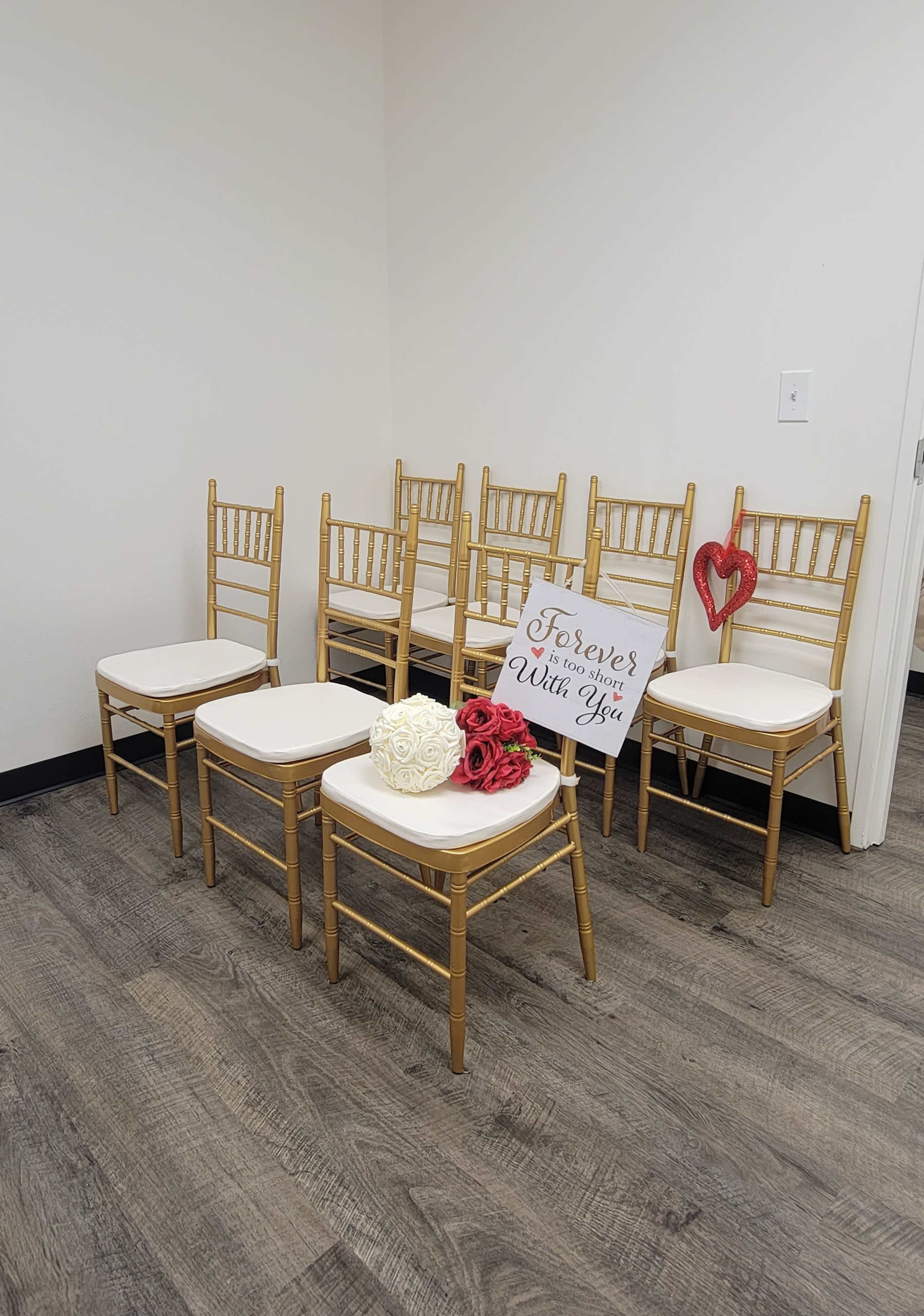 A row of golden chairs is arranged against a wall, with a sign that says "Forever and Always with You" and decorative flowers placed nearby.
