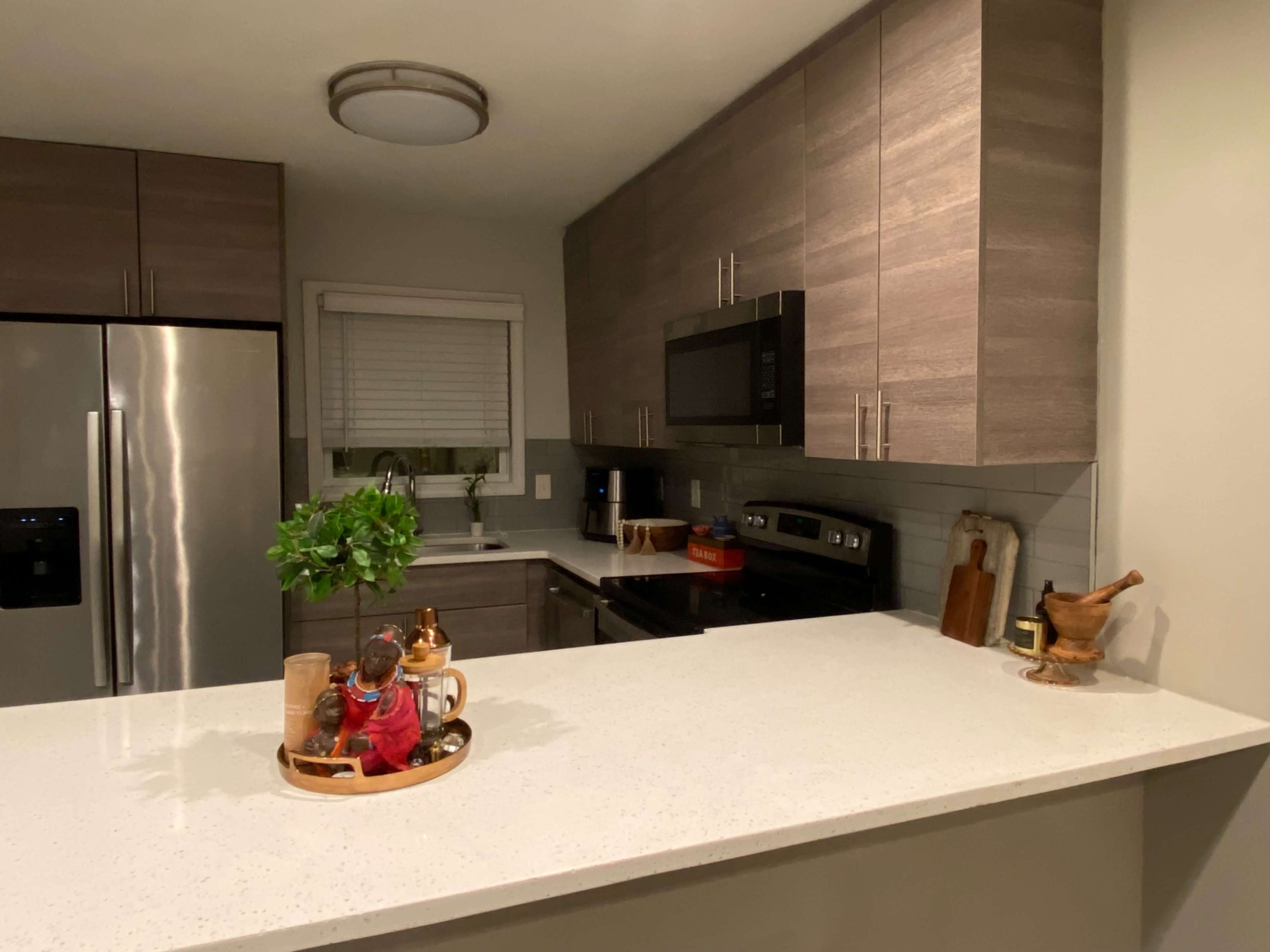 A modern kitchen with gray cabinets, stainless steel appliances, and a countertop featuring decorative items.