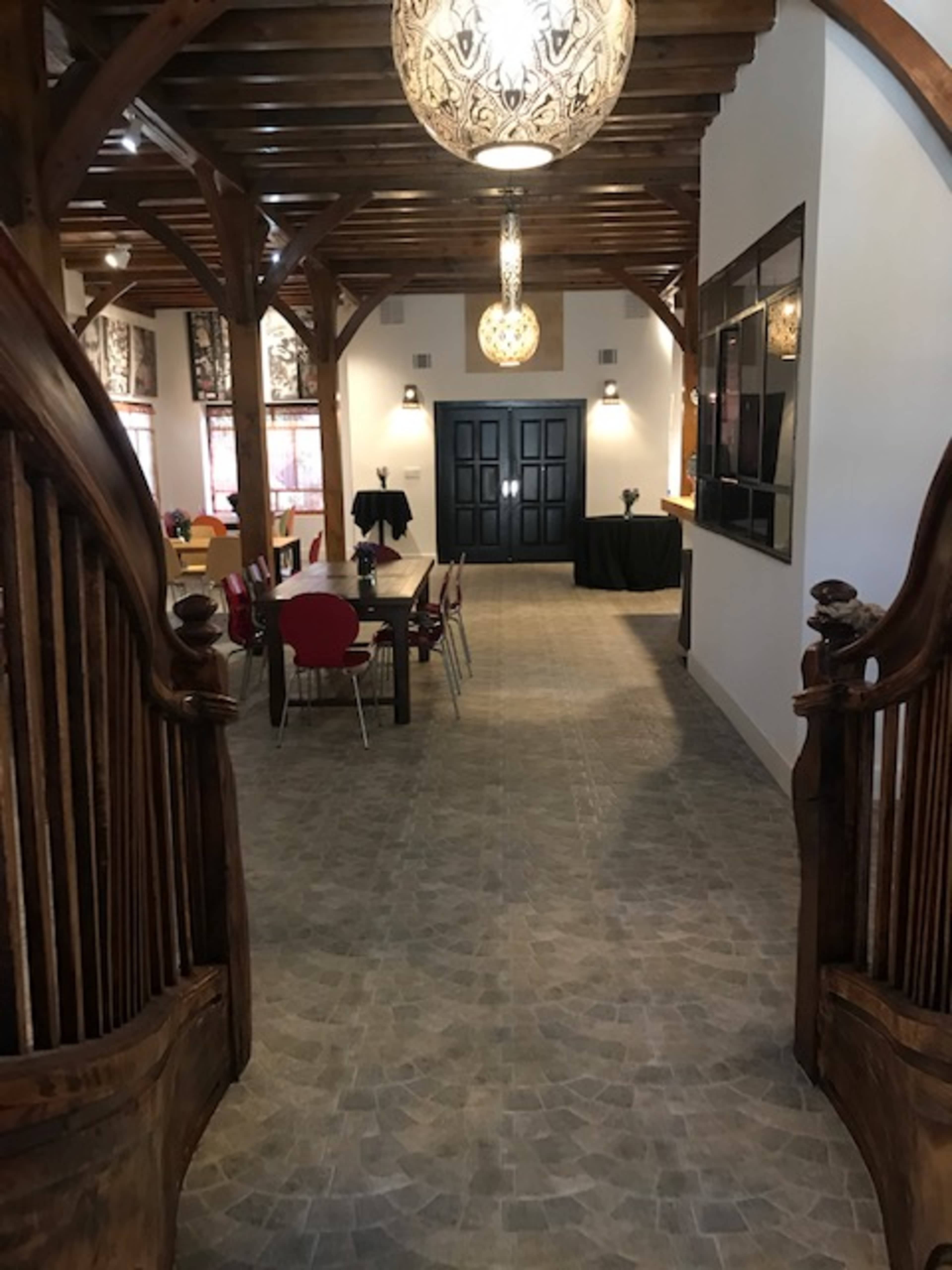 A spacious interior with a large entrance featuring wooden arches, a tiled floor, and decorative lighting fixtures.