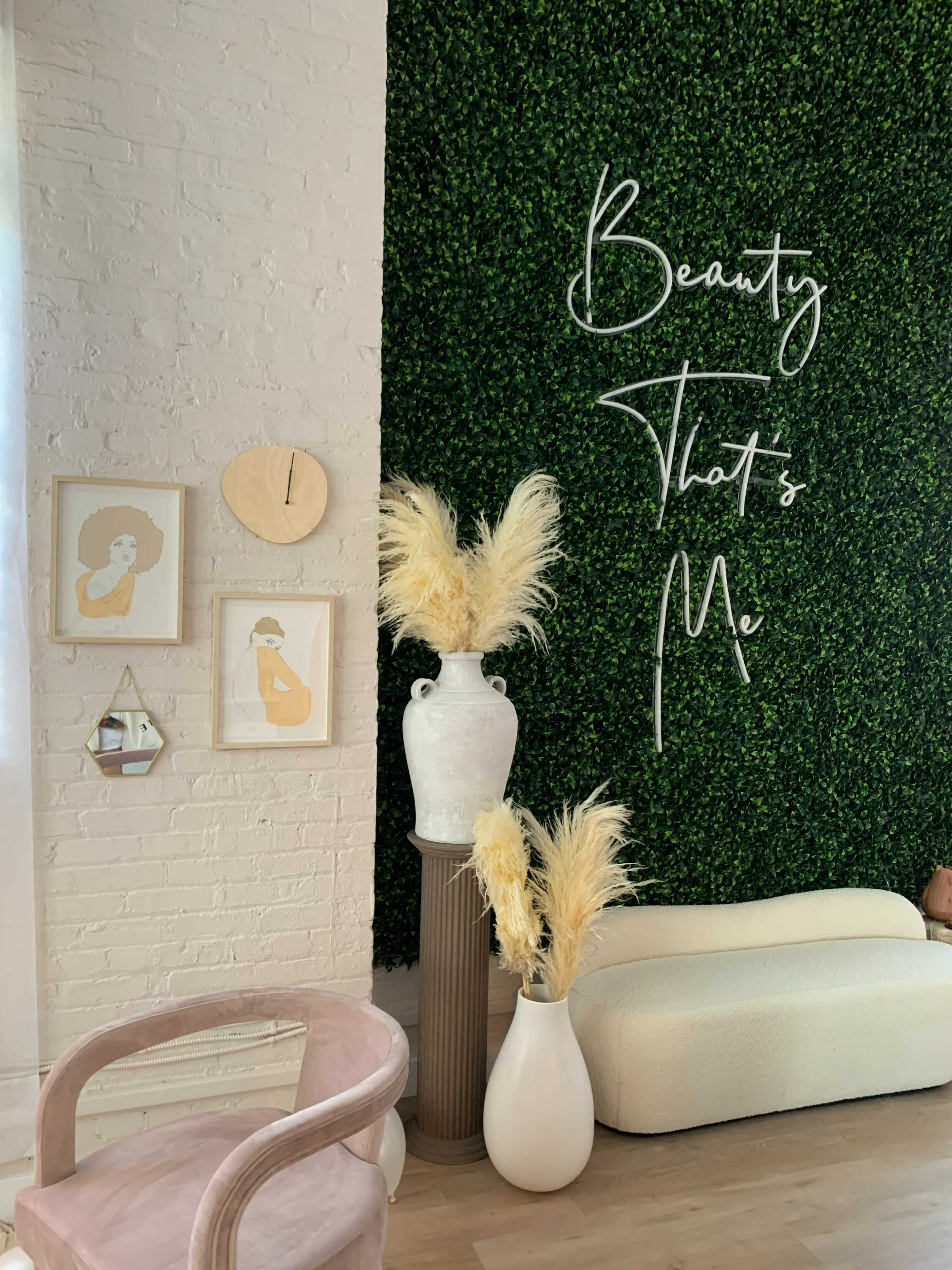 The image shows a stylish interior featuring a green wall, decorative wall art, a clock, and vases with dried pampas grass.