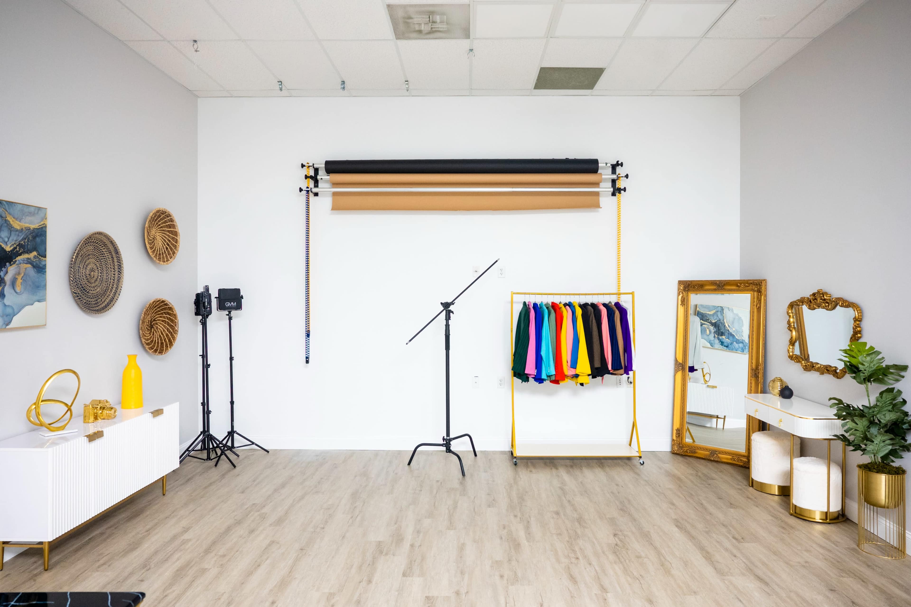 A photography studio with backdrops, colorful clothing hanging on a rack, and various decorative elements.