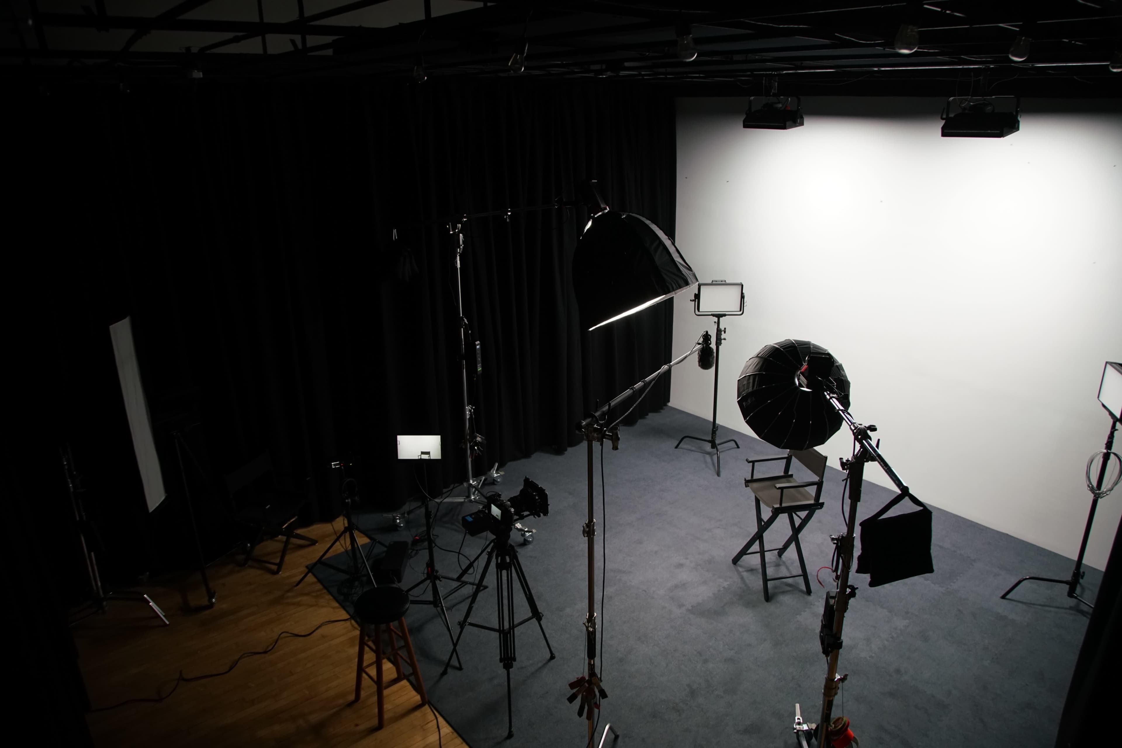 A photography studio equipped with lighting equipment, a chair, and a backdrop.