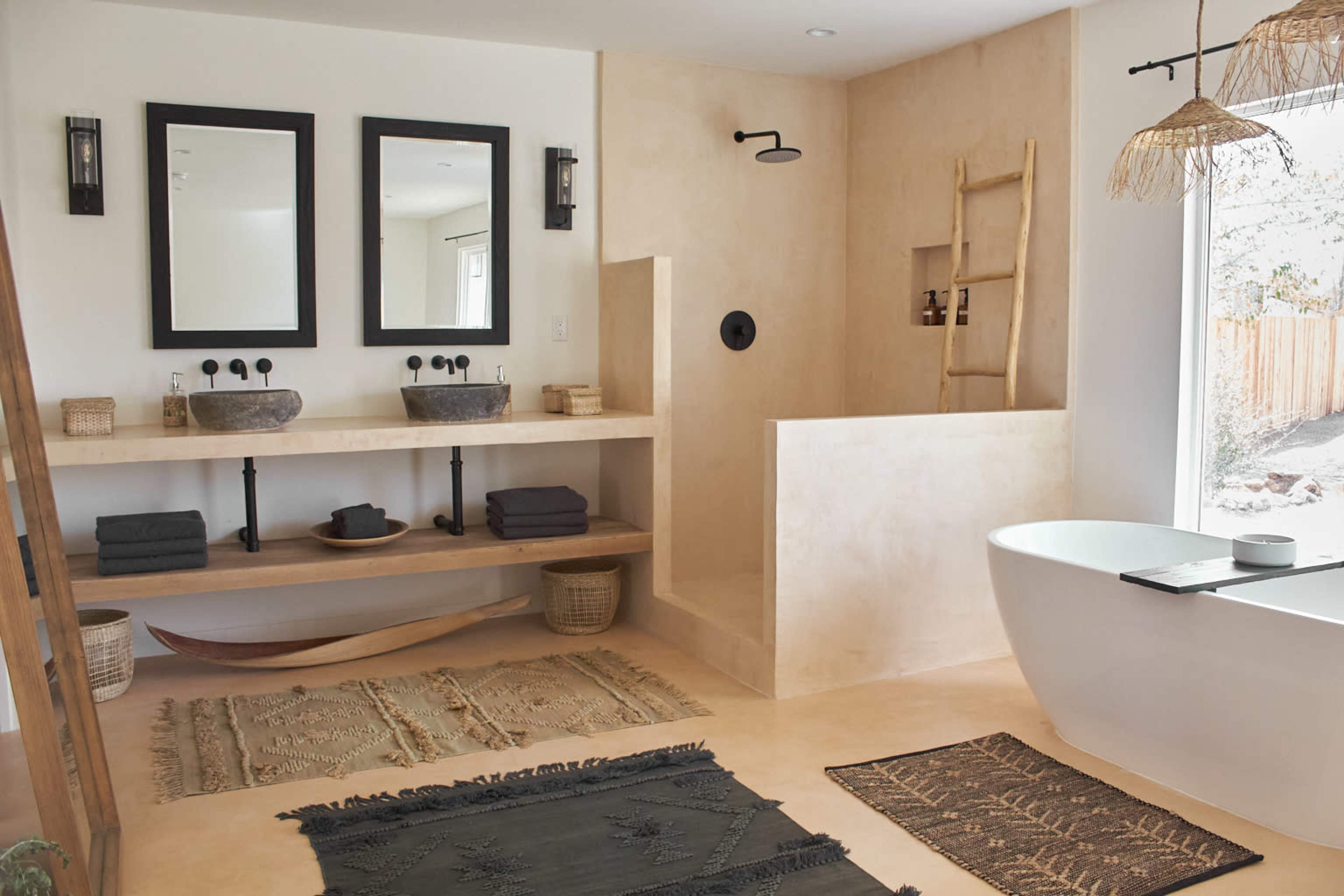 A modern bathroom features a freestanding tub, a spacious shower area, dual vanities with sinks, and a minimalist aesthetic with natural materials and neutral tones.
