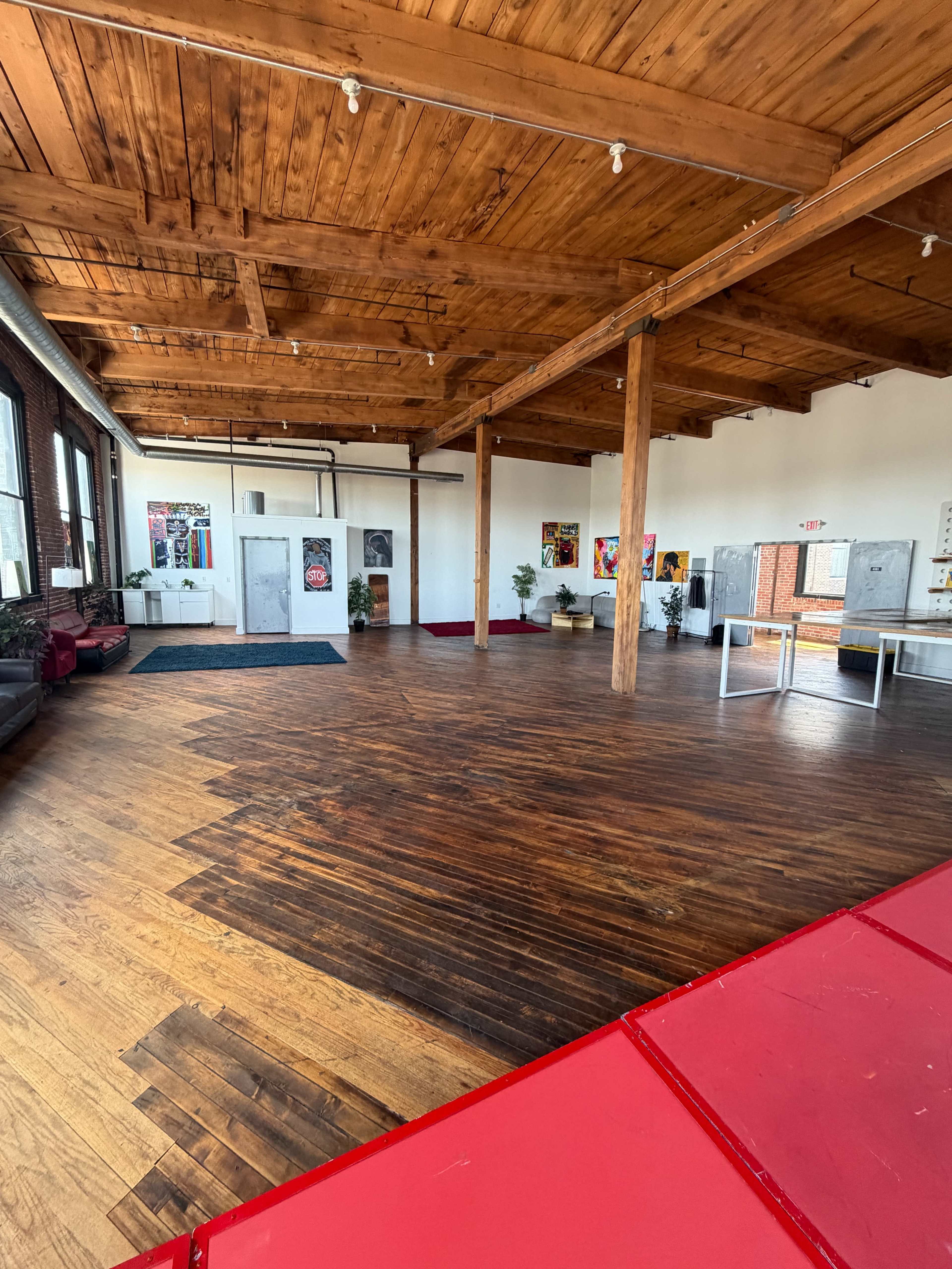 The spacious interior features polished wooden floors, exposed beams, and colorful artwork on the walls.