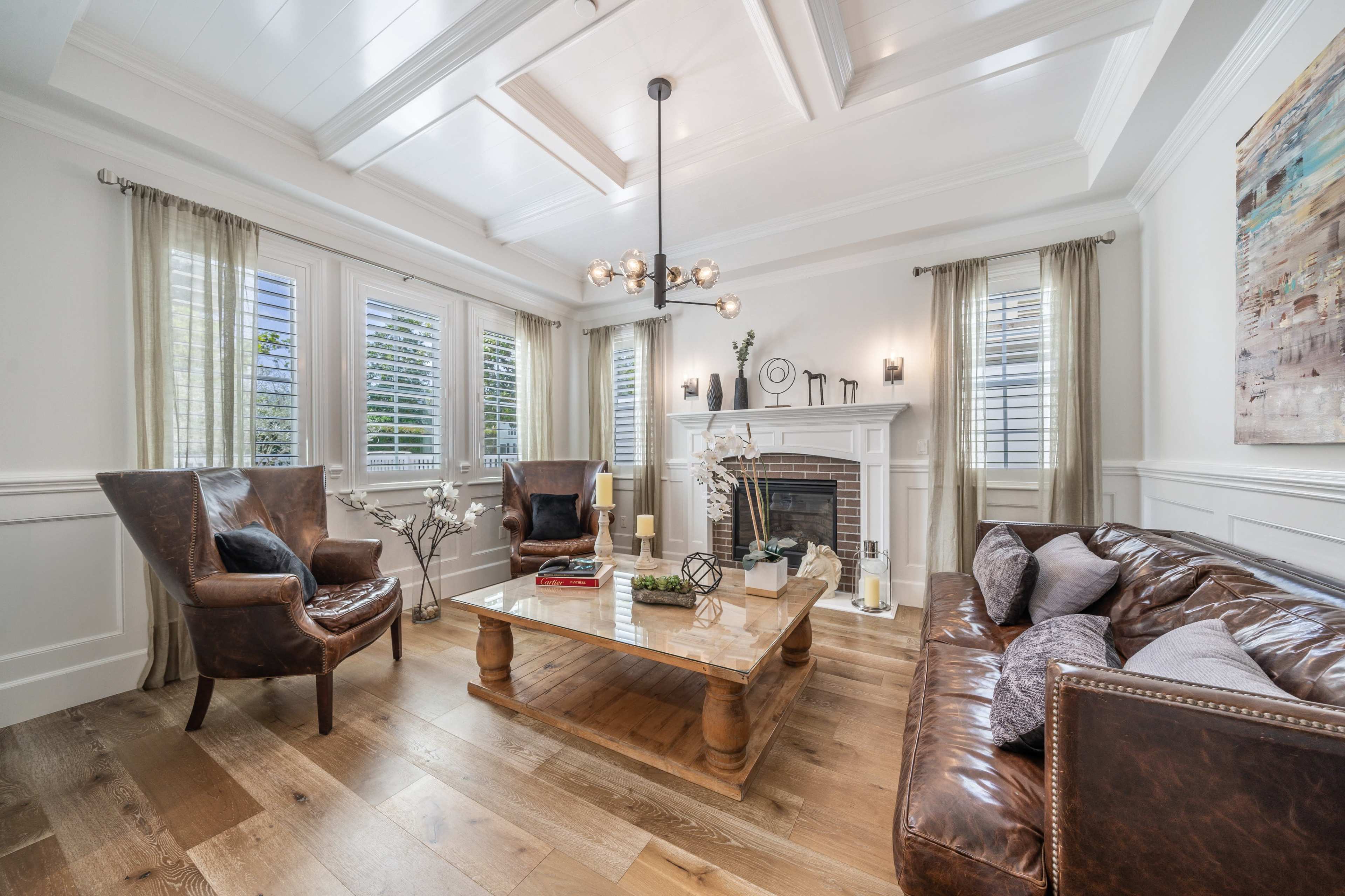 A bright living room with a fireplace, two armchairs, a leather sofa, and a wooden coffee table.