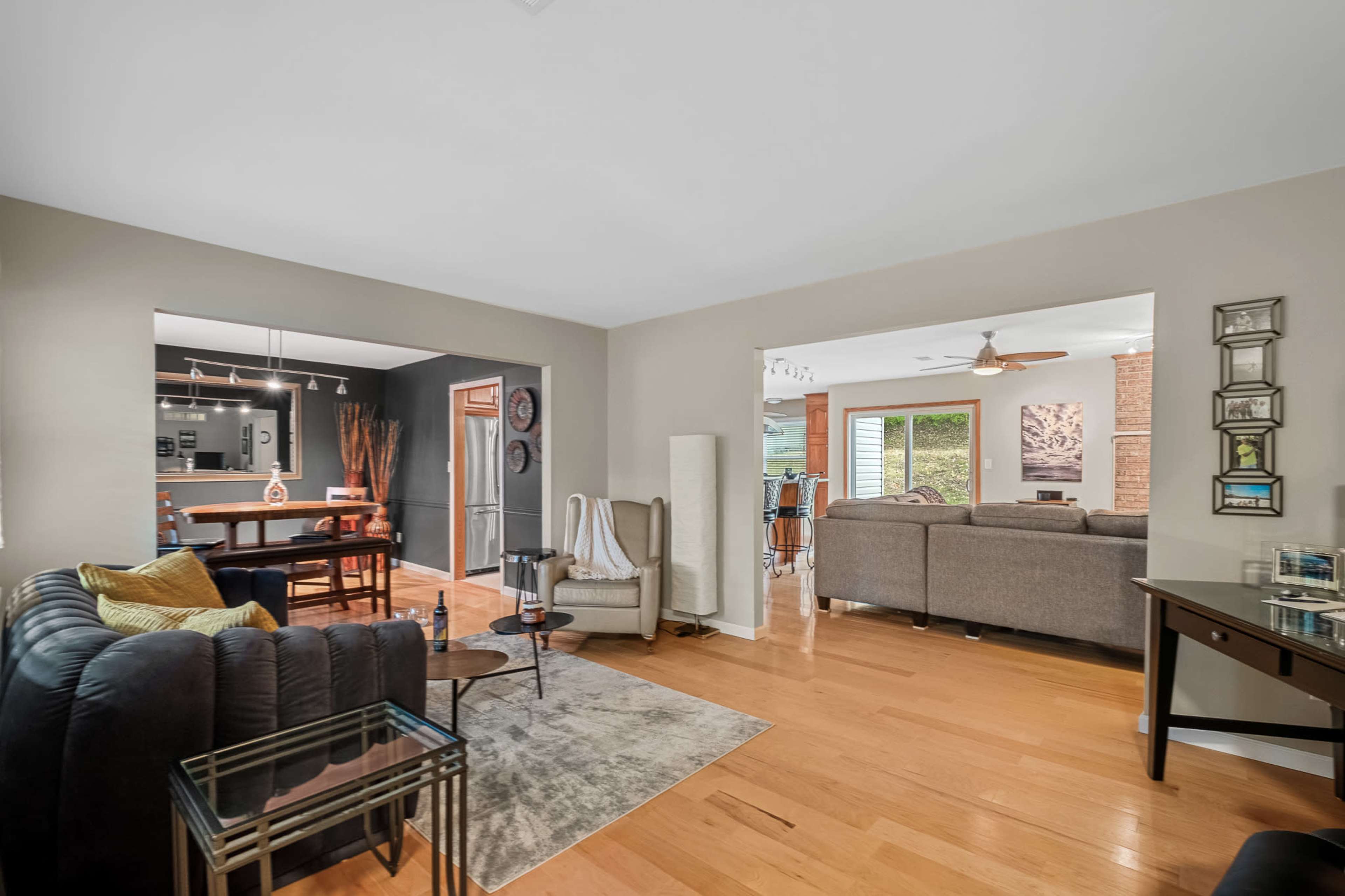 A modern living space with a dining area on one side and a cozy seating arrangement on the other, featuring hardwood floors and neutral wall colors.