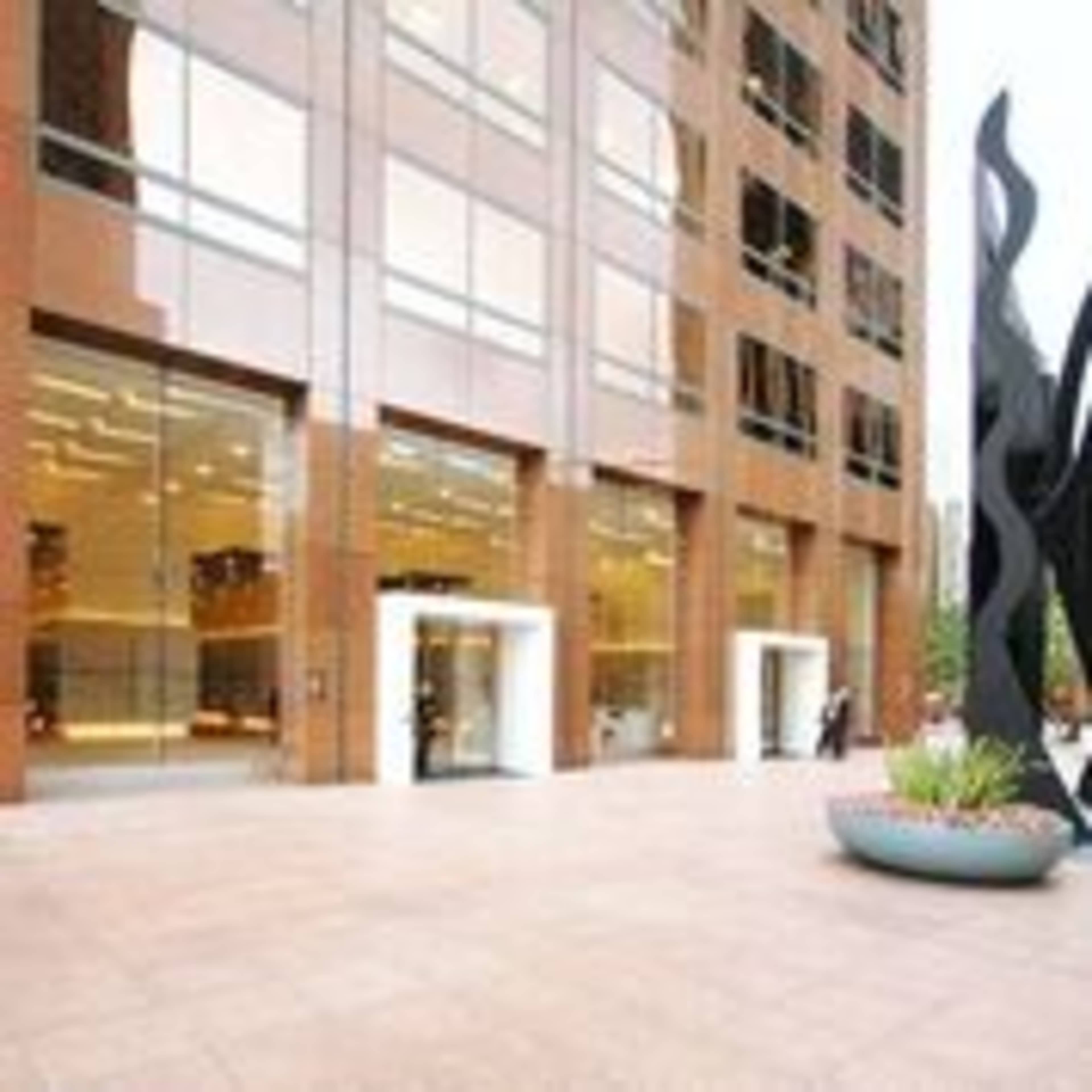 A modern building with a glass entrance and a tall abstract sculpture in front.