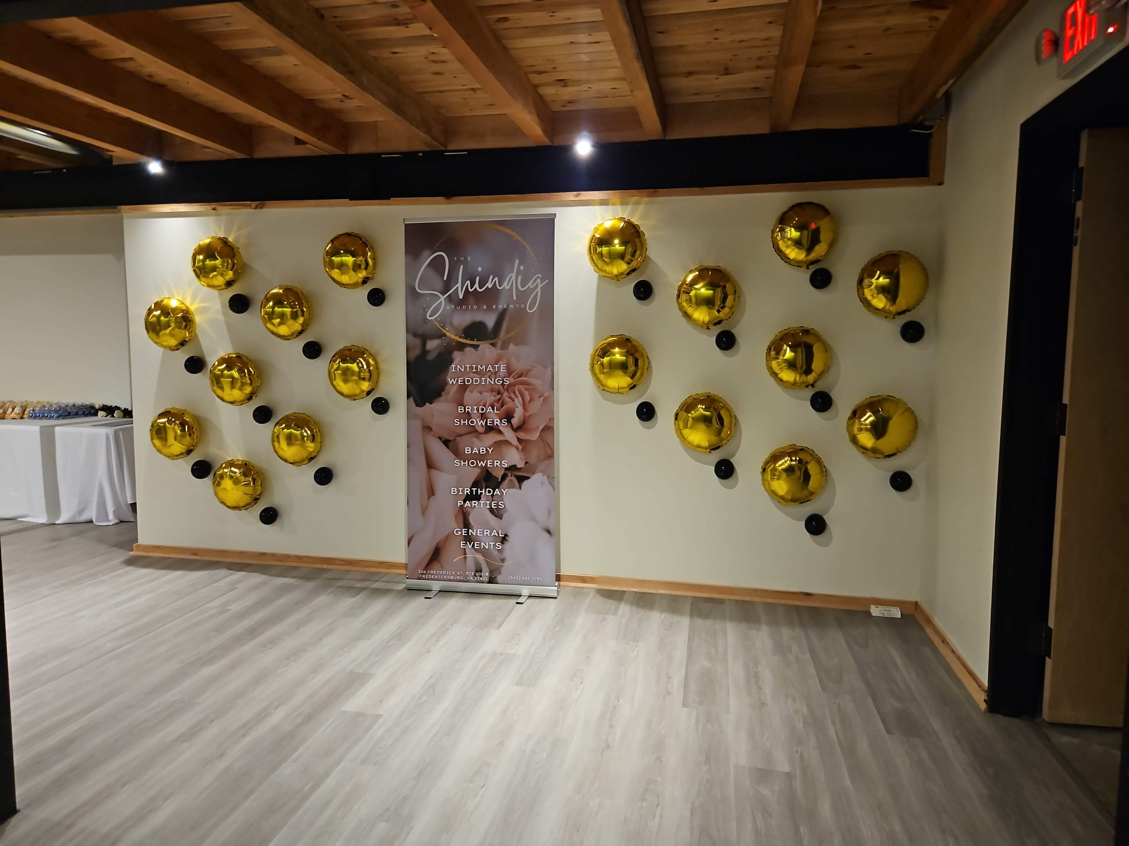 A wall adorned with gold balloons and a banner featuring the word "Shining" along with various event names and details.