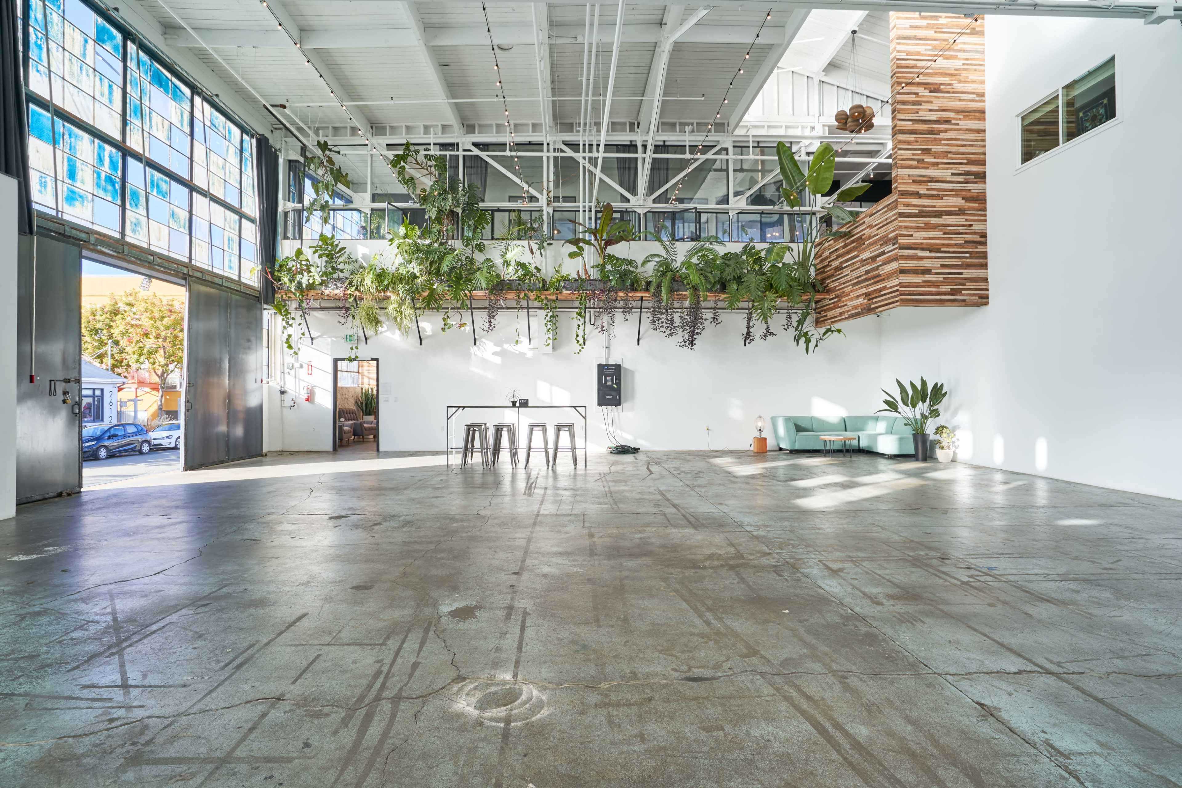 A spacious, modern interior with high ceilings, large windows, and greenery adorning the walls.