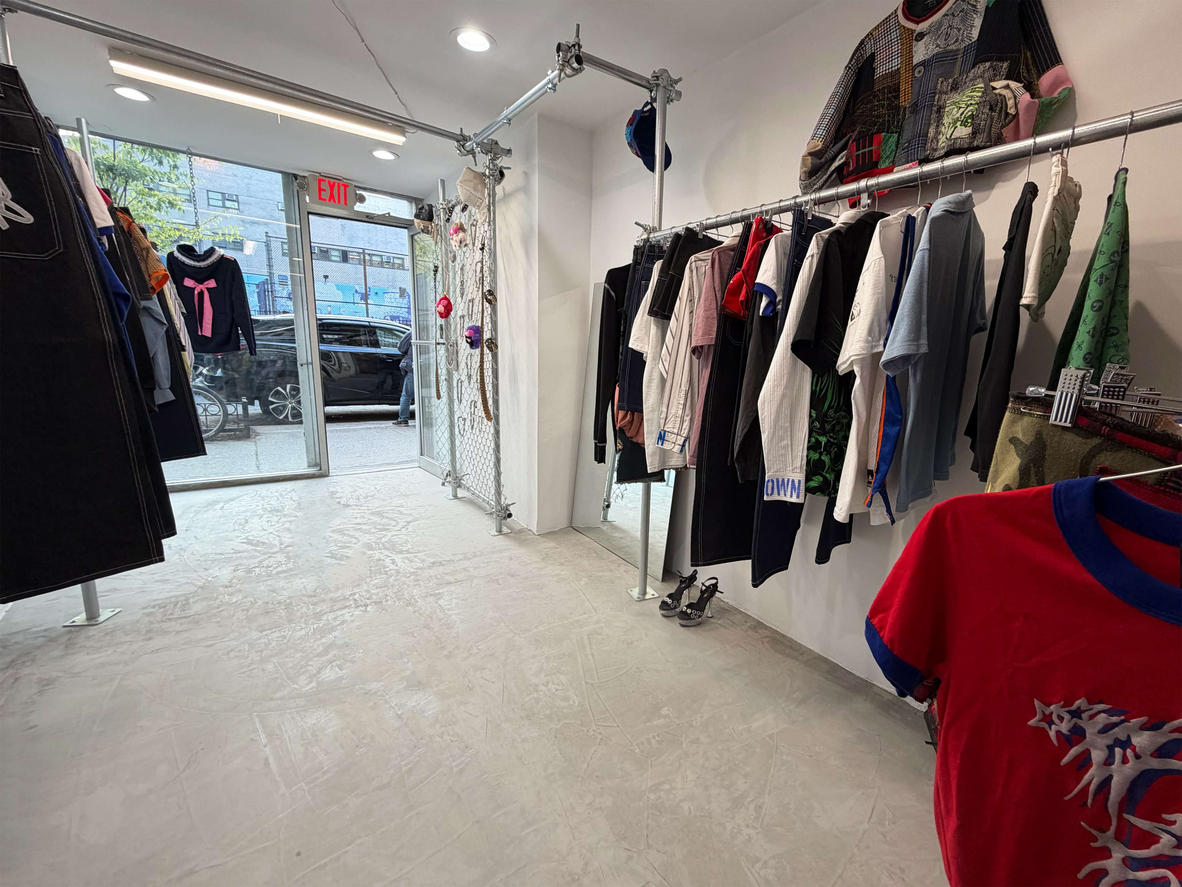 A retail clothing store displays various shirts and pants on racks, with a clear entrance visible at the front.