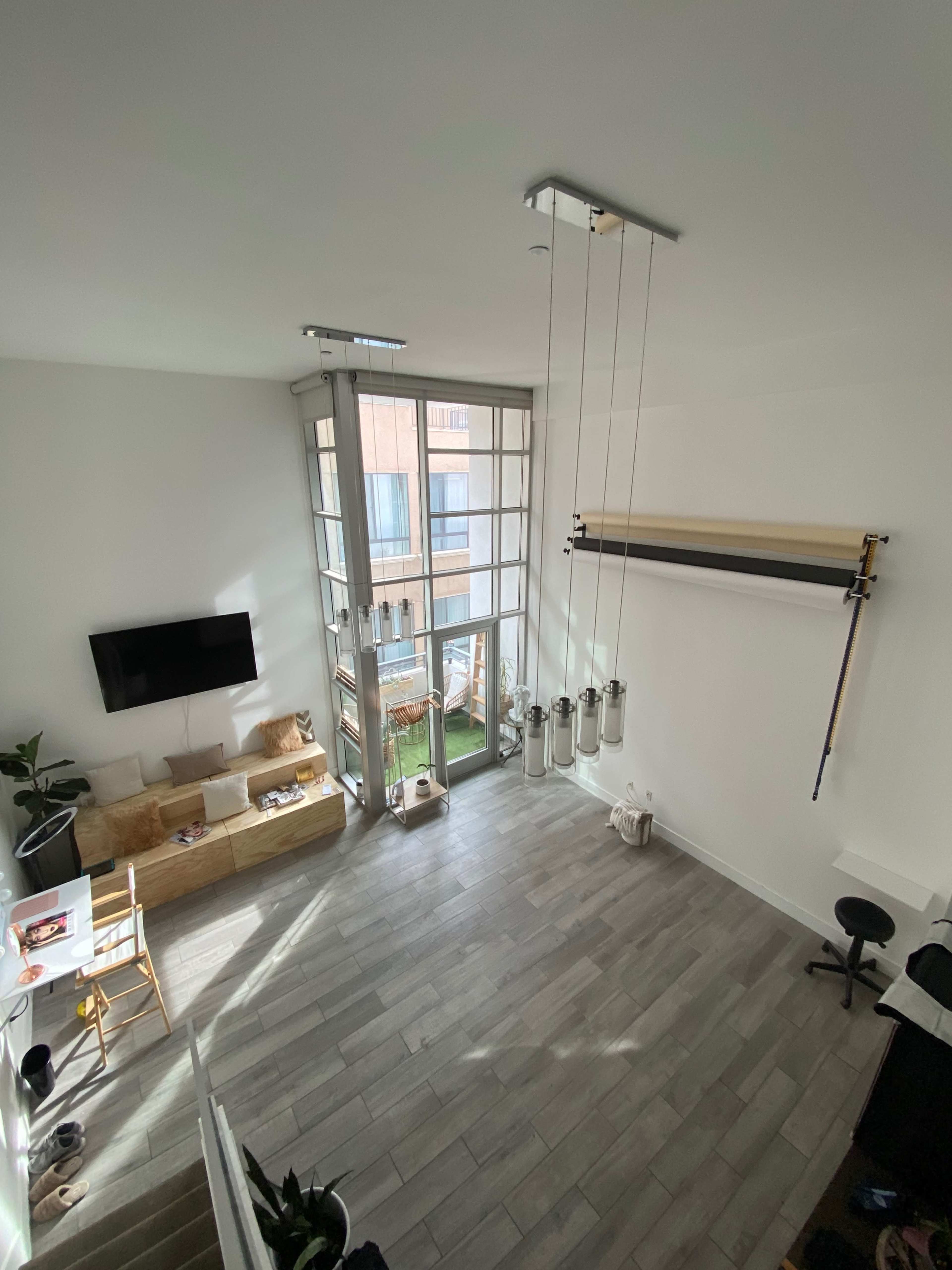 A spacious, modern living area with large windows, a staircase, and a balcony leading to an outside space.