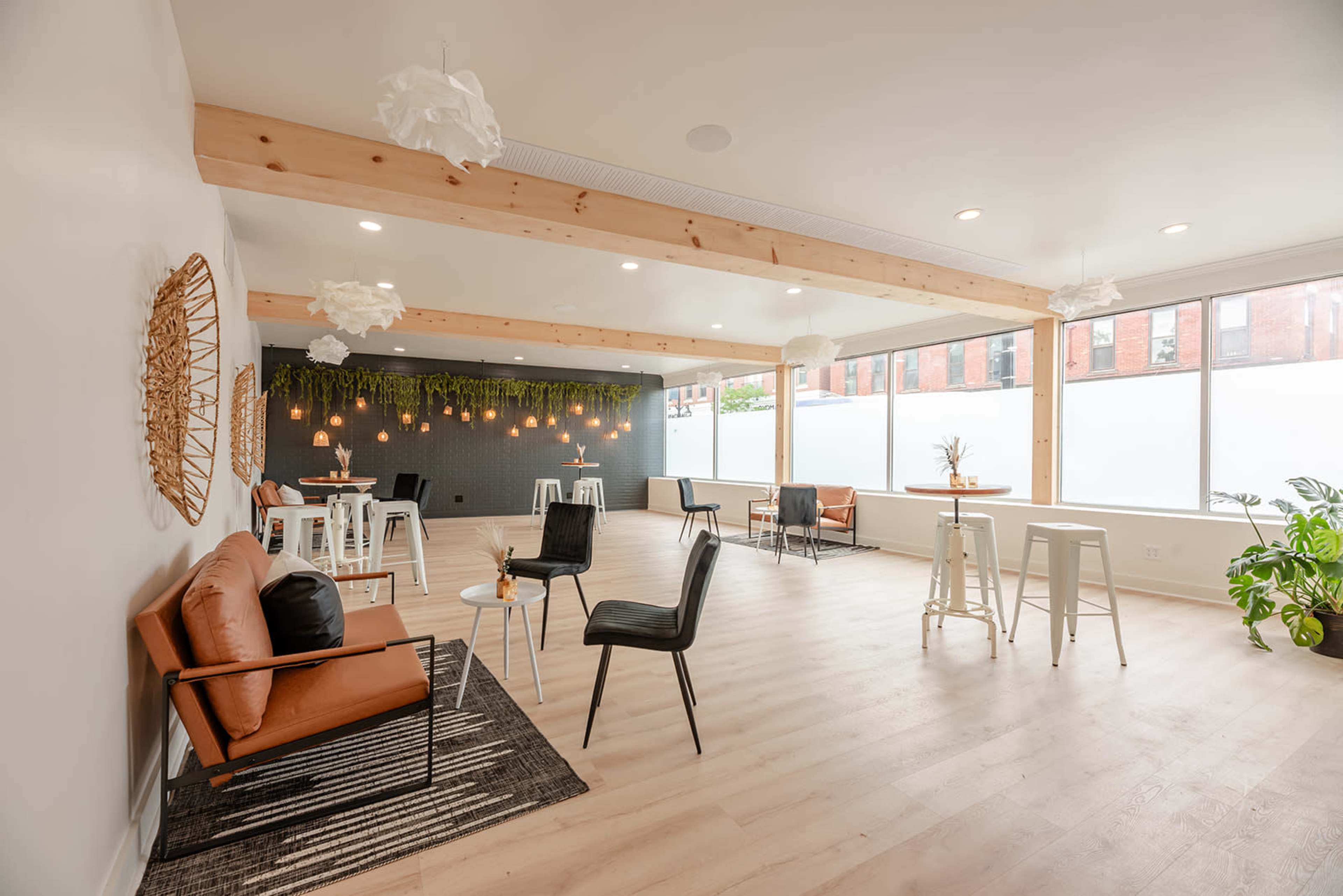 A modern interior space featuring wooden beams, a mix of seating arrangements, and decorative plants.