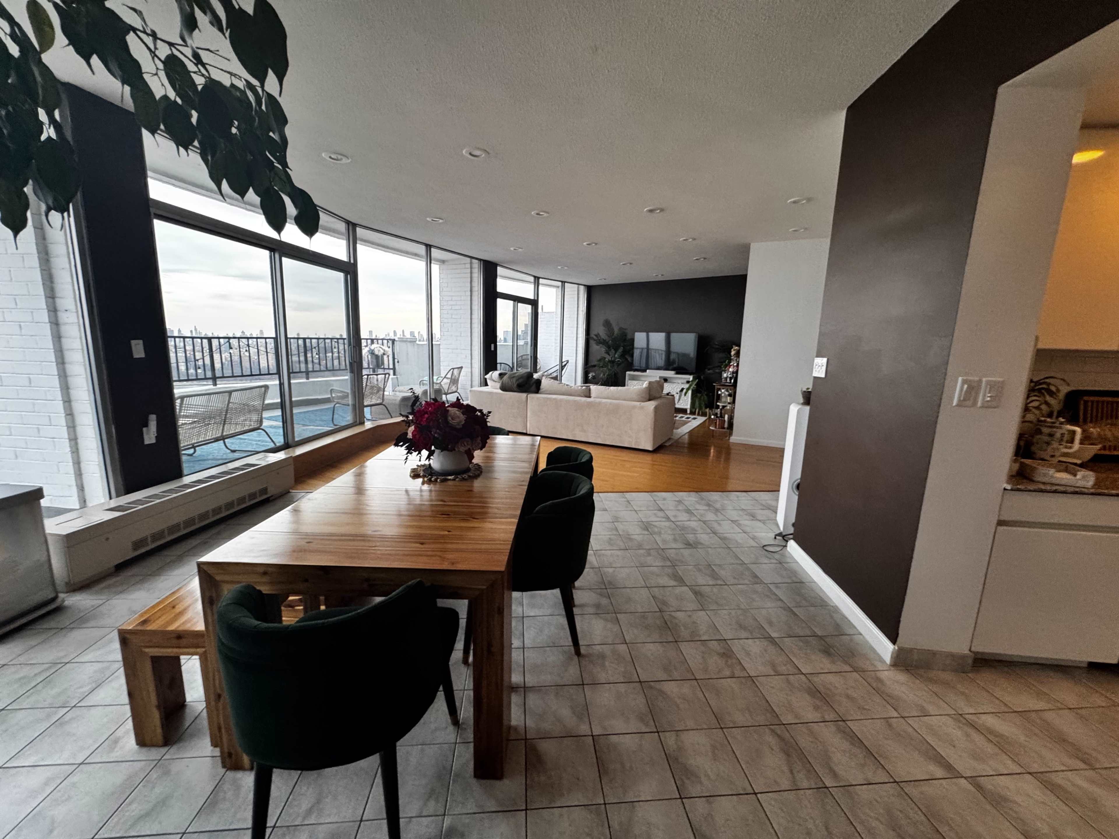 The image shows a modern open-concept living space with a dining area and large windows overlooking a waterfront view.