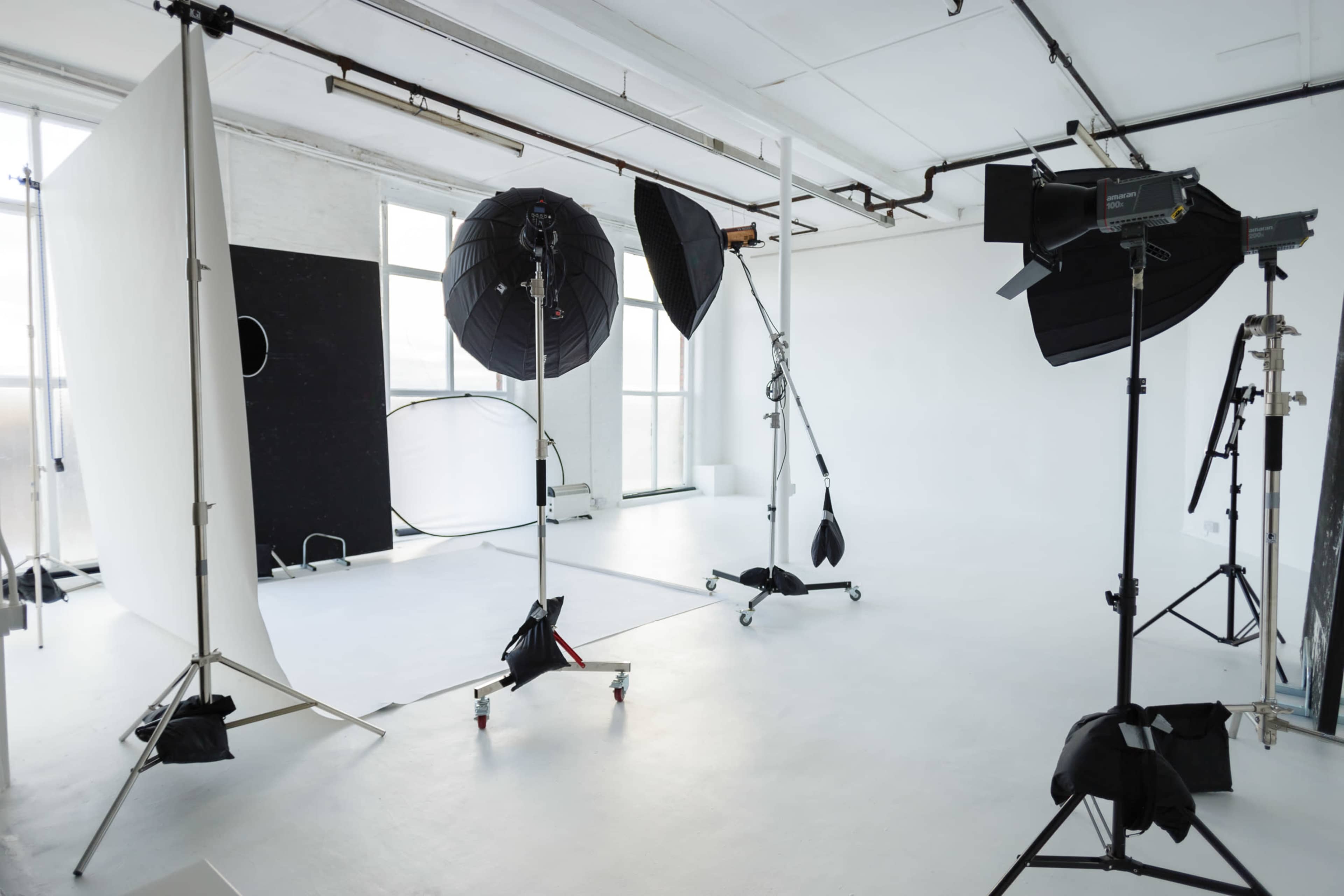A photography studio equipped with lighting equipment, backdrops, and stands in a spacious, well-lit area.