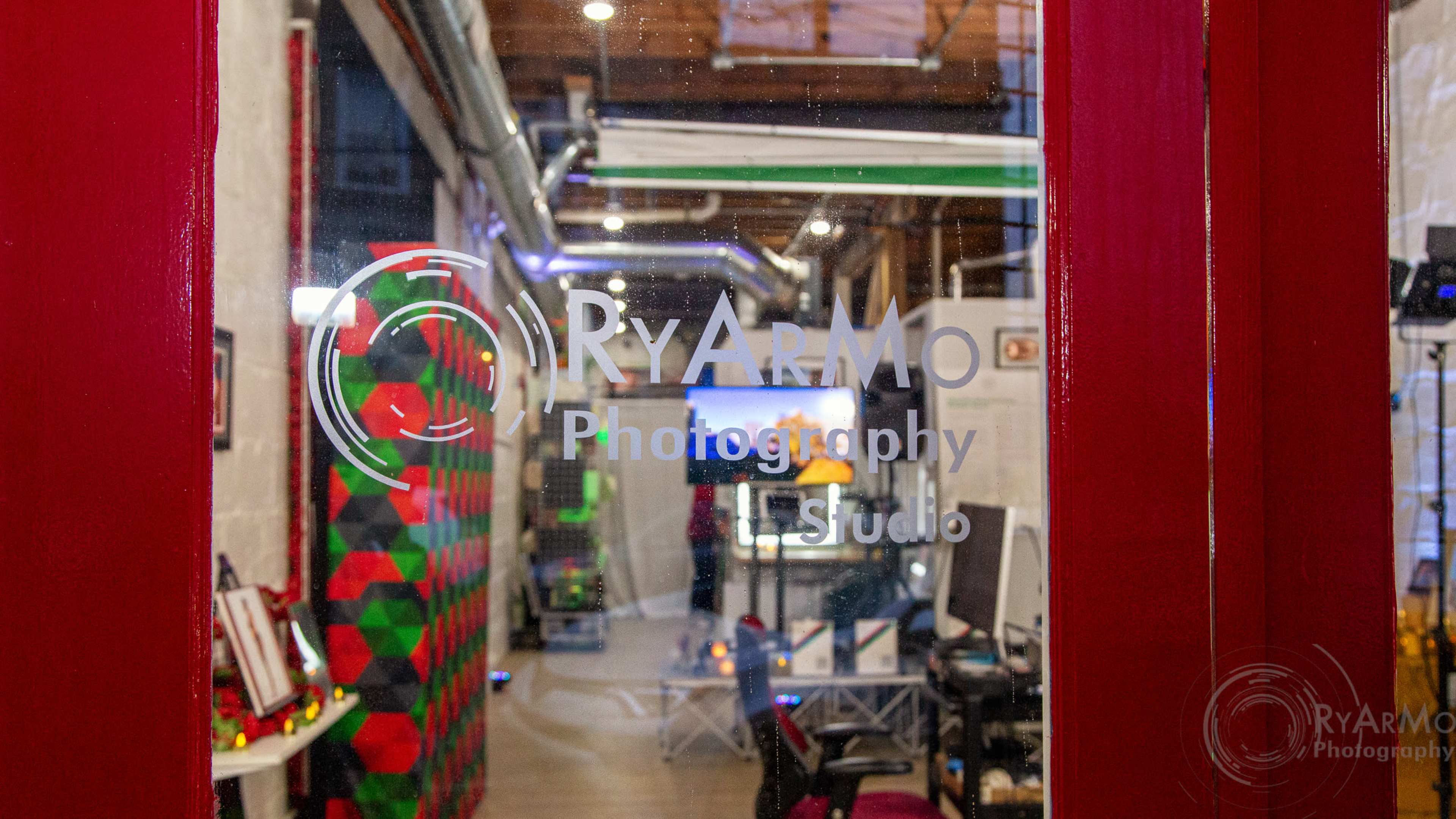 A clear glass door displays the logo of "RyarMo Photography" along with the interior of a photography studio visible through the glass.