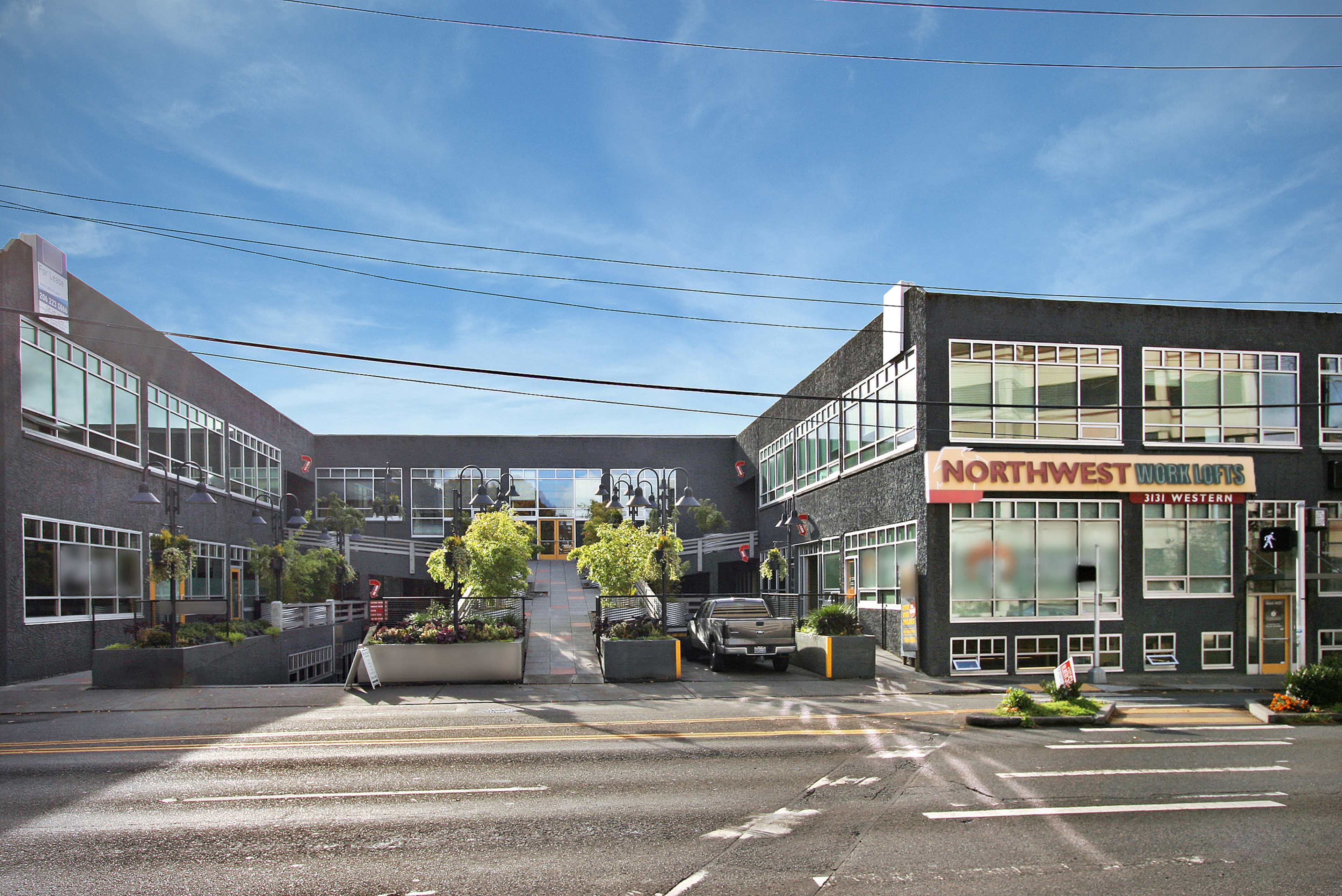 A modern, two-story commercial building with large windows and a prominent sign that reads "NORTHWEST" on the right side, located on a street lined with trees and planters.