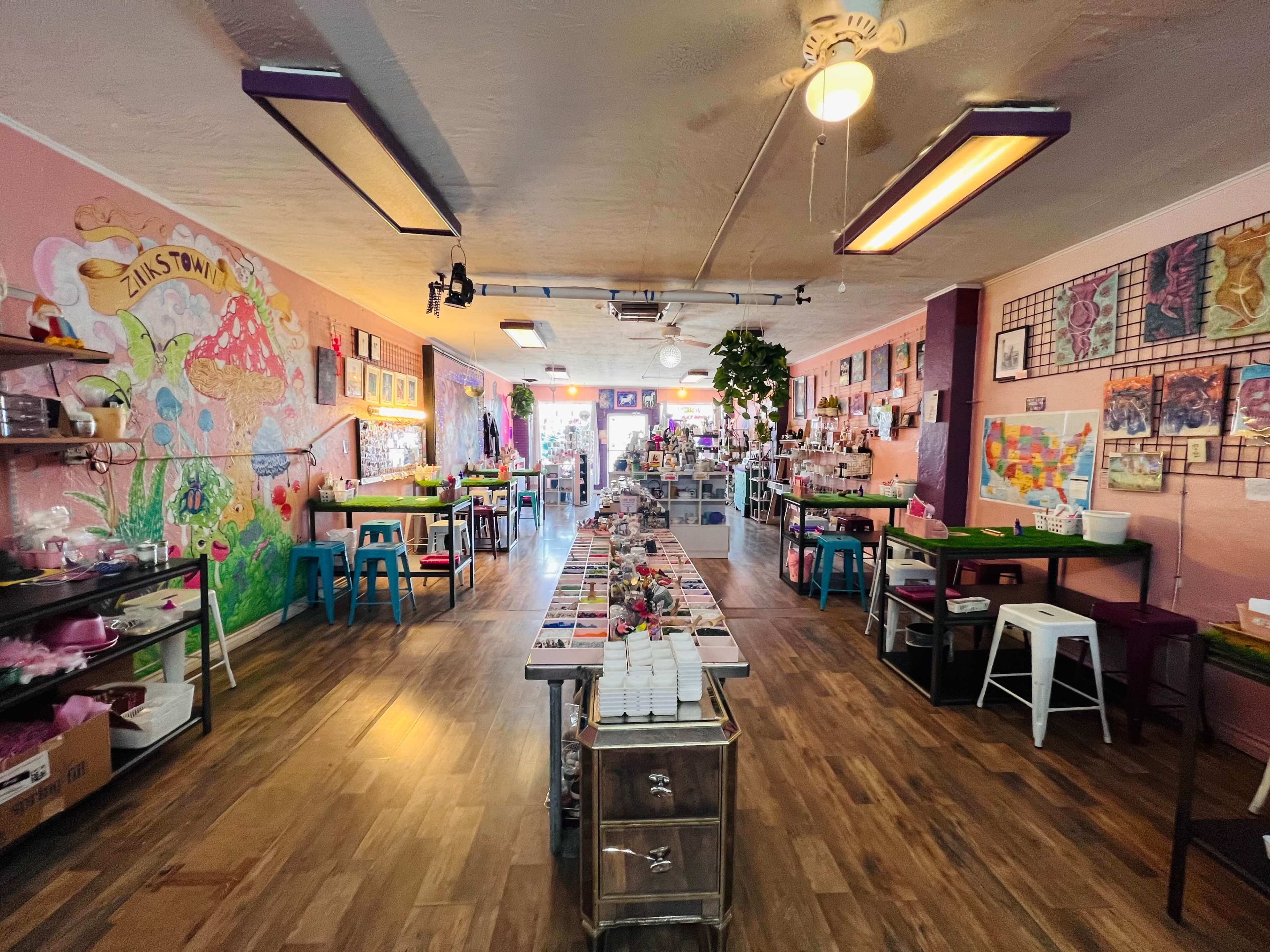 A colorful retail space with various displays, tables arranged down the center, and artwork on the walls.