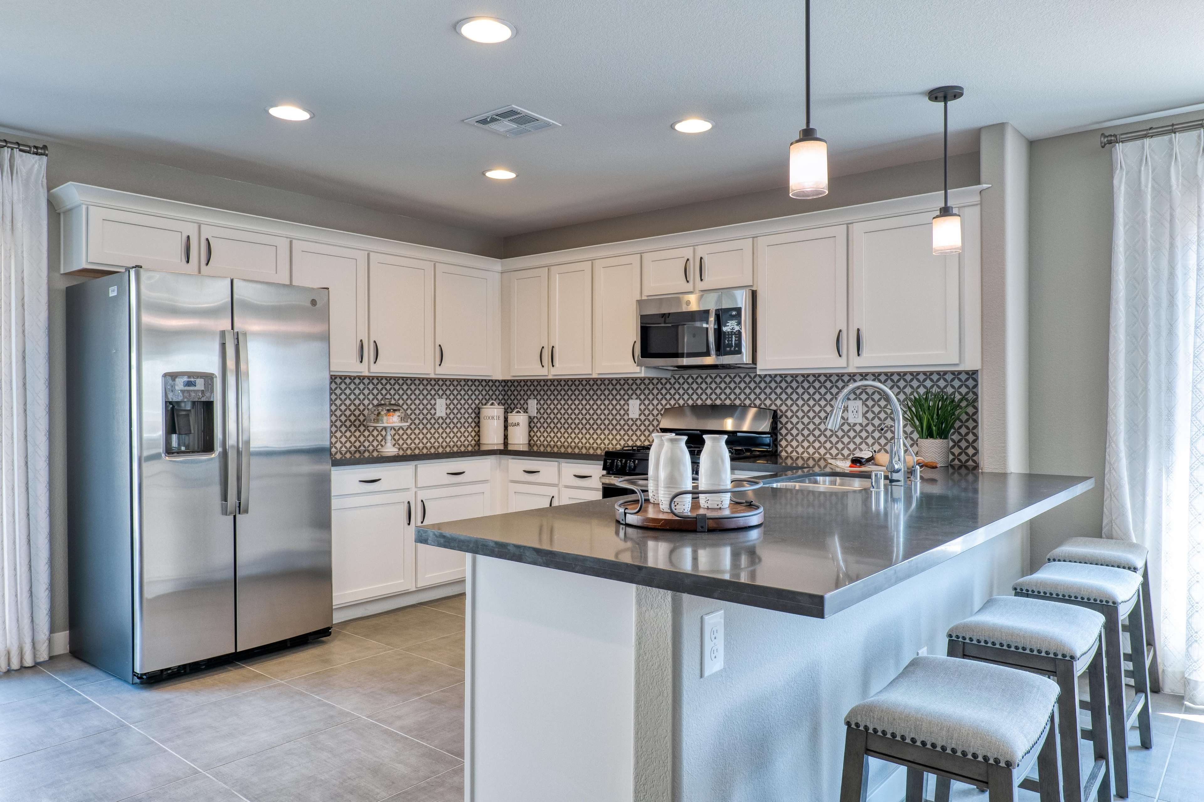 A modern kitchen with white cabinets, stainless steel appliances, and a large island with bar stools.