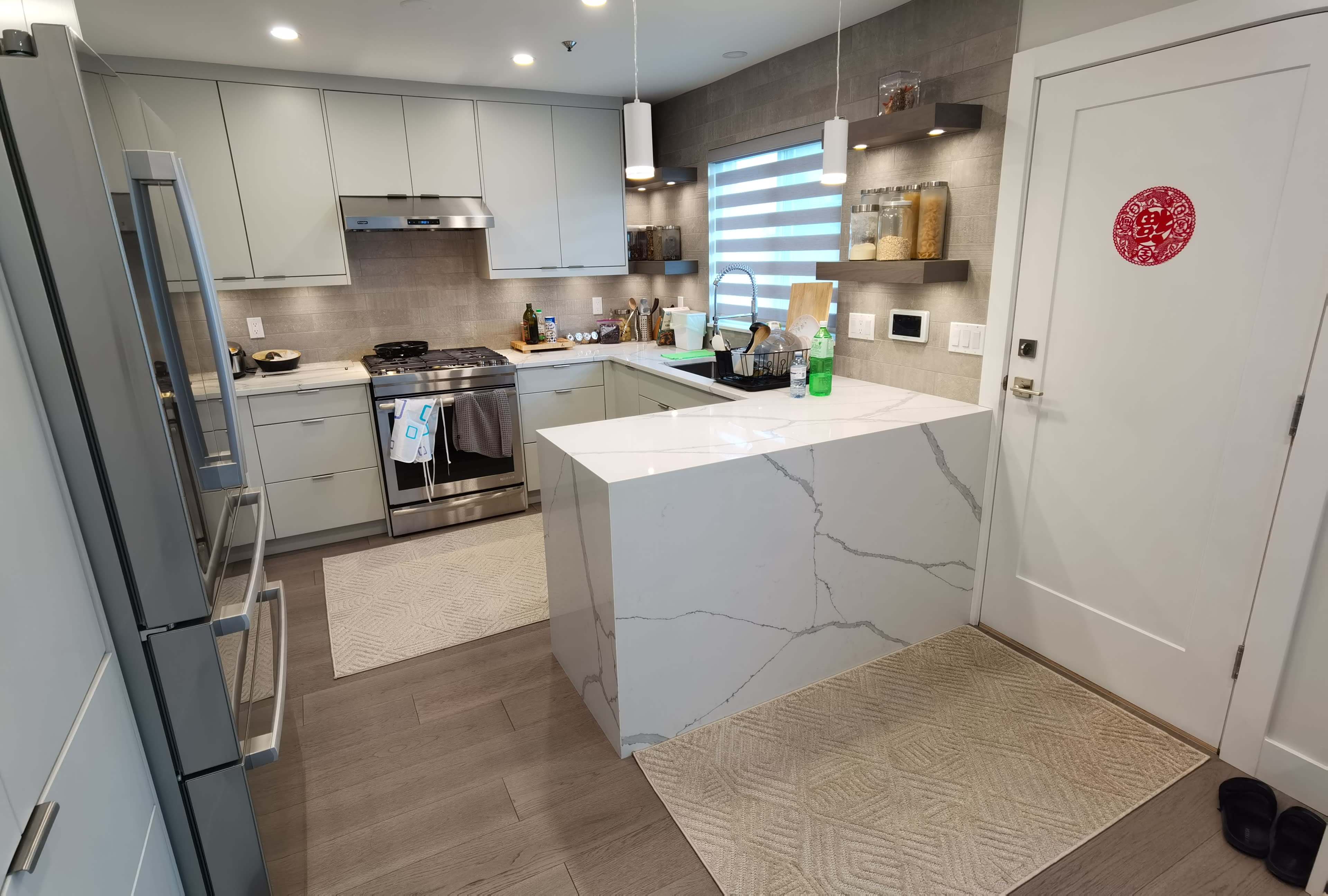 A modern kitchen with sleek cabinetry, a central island with a marbled countertop, and appliances including a gas stove and refrigerator.